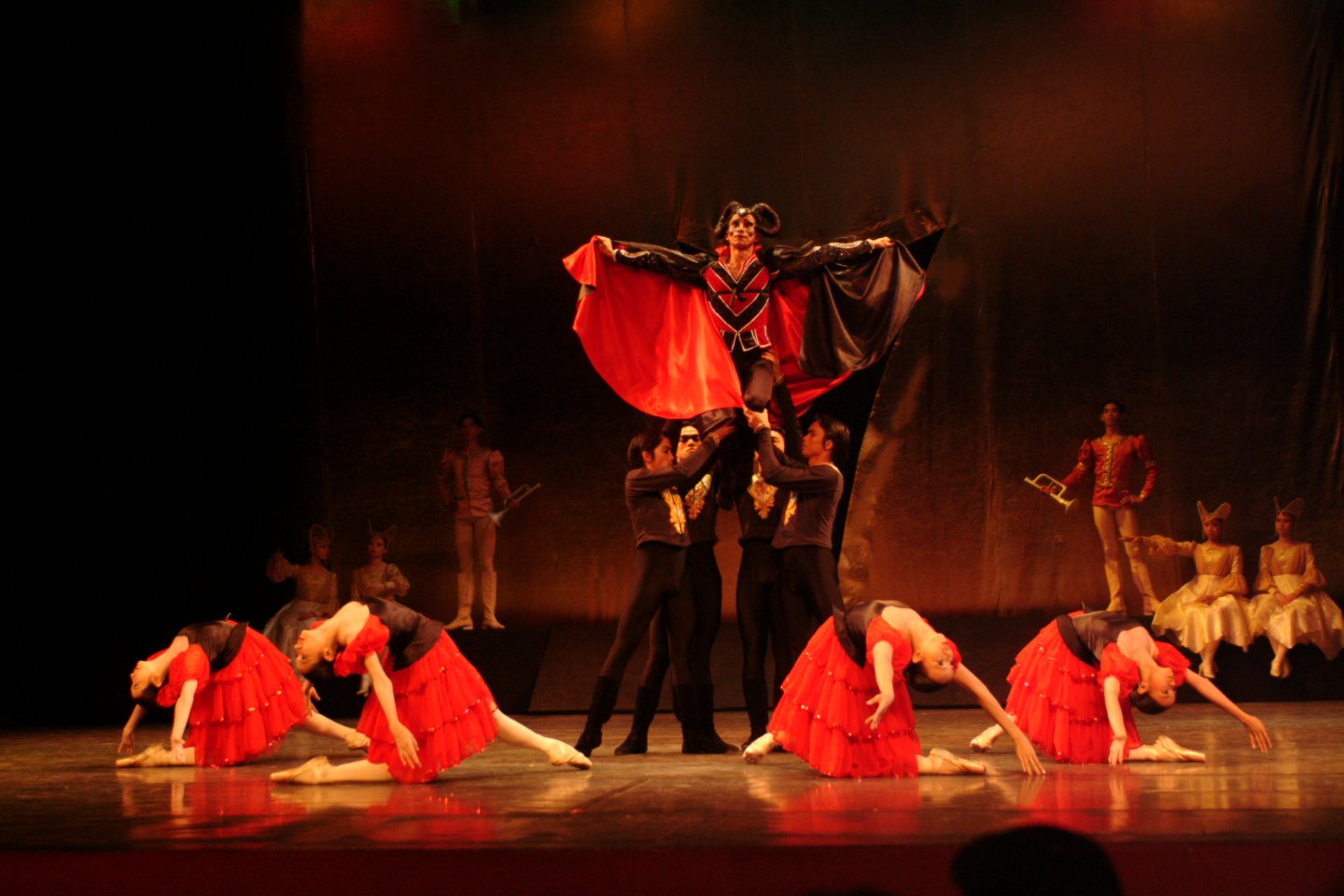    The sorcerer Rothbart (Eduardo Espejo), wearing a predominantly red cape, makes sure all eyes are on him as he makes his grand entrance at the palace where he is about to unleash his evil scheme in  Swan Lake  (2003). The fiery color is underscore