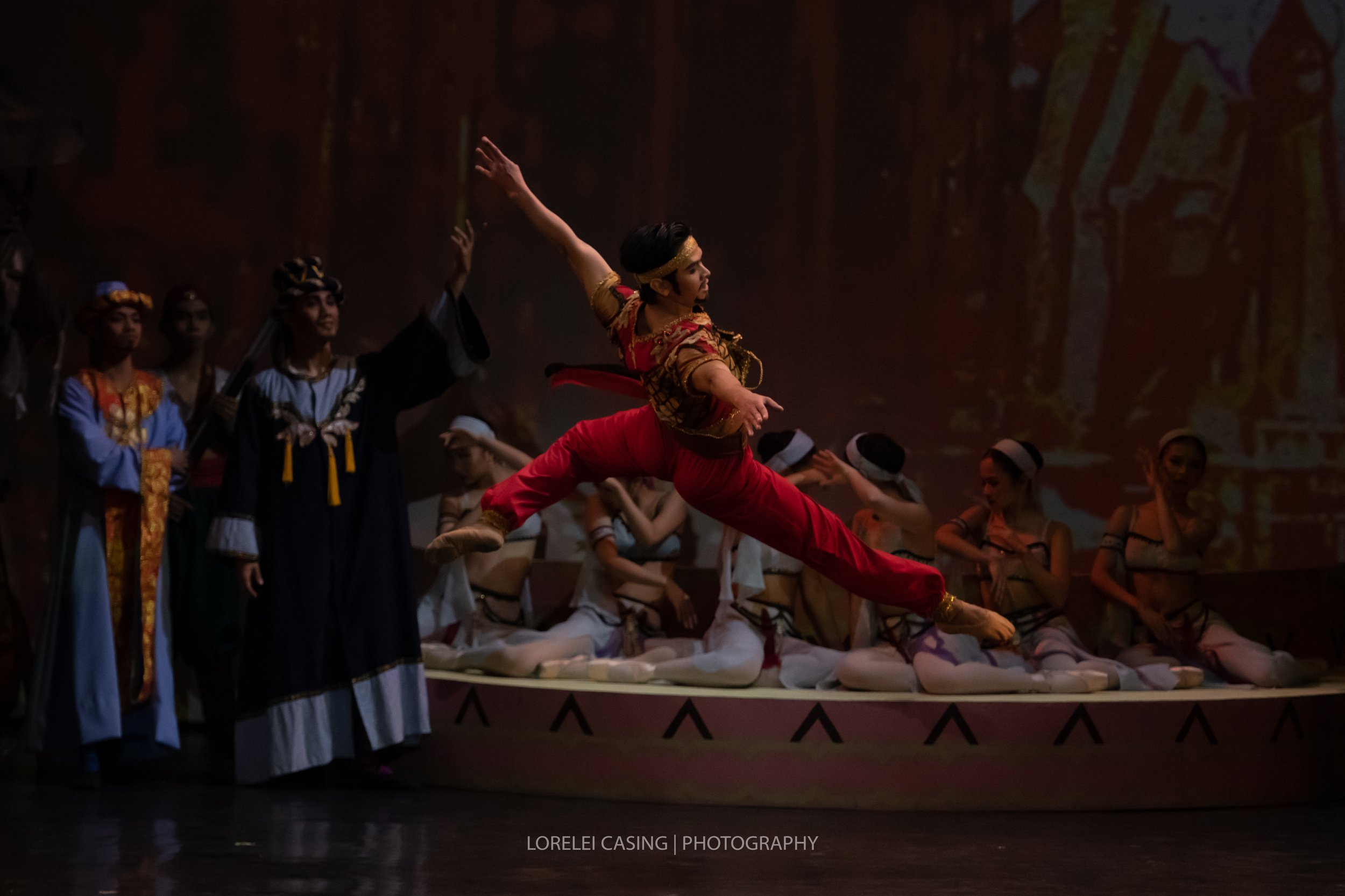    In  Le Corsaire  (2018), Lankadem (Rudy De Dios) is a forbidding figure in red, feared by the women he is to sell off as slaves, and relied on by the wealthy who spare no expense in procuring his services to supply their harem. Photo by Lorelei Ca