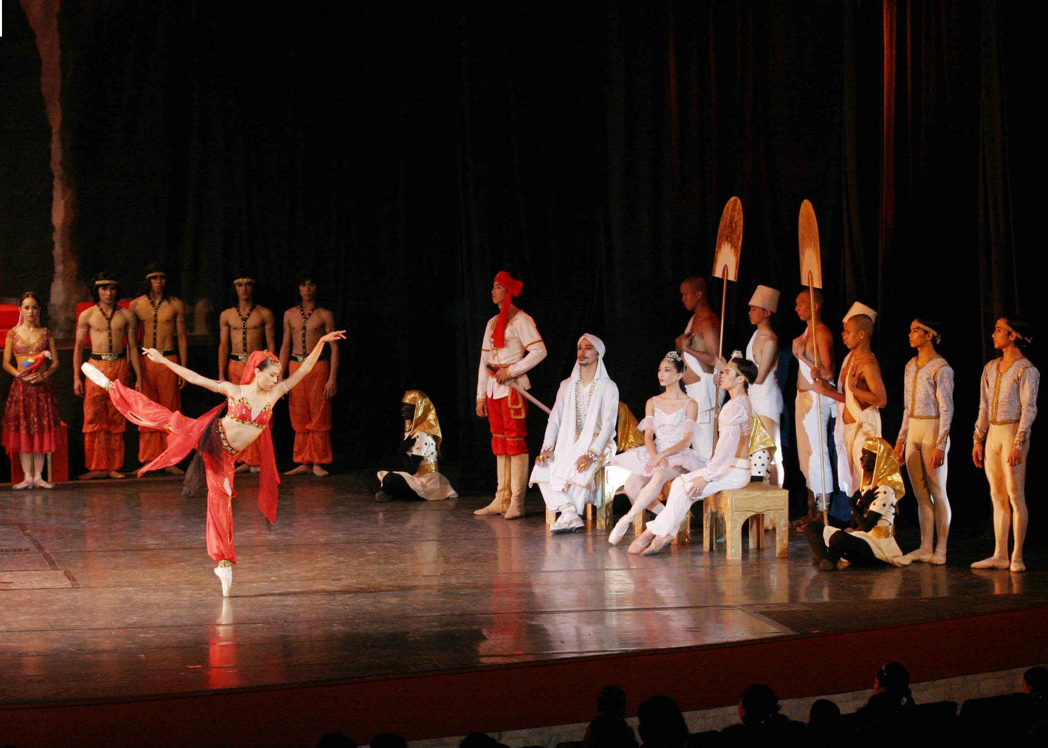    Fans are the essential symbol of royalty in this scene from  La Bayadere  (2004), where a pair of fan-bearers (right) are ready to spring into action as needed while they stand behind the Rajah, his daughter Gamzatti and her betrothed Solor as the