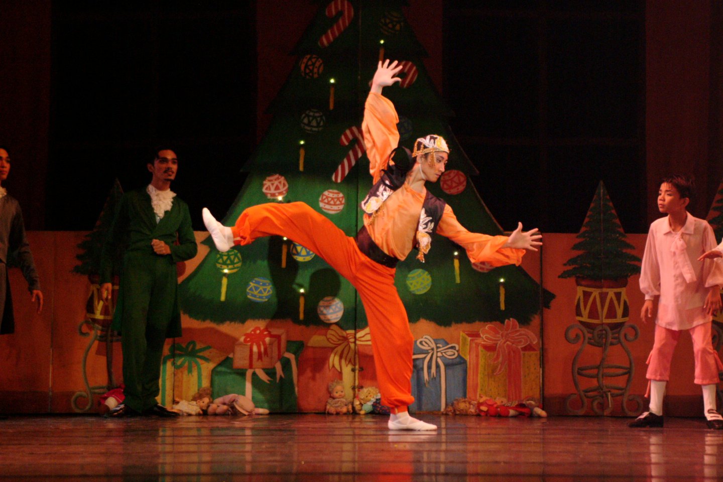    Flashy in color and dynamic in movement, the orange-wearing Moor (Lemuel Capa) makes quite a spectacle at the Christmas Eve festivities in  The Nutcracker  (2003). Along with the Harlequin and the Doll, the Moor has been brought along by Uncle Dro