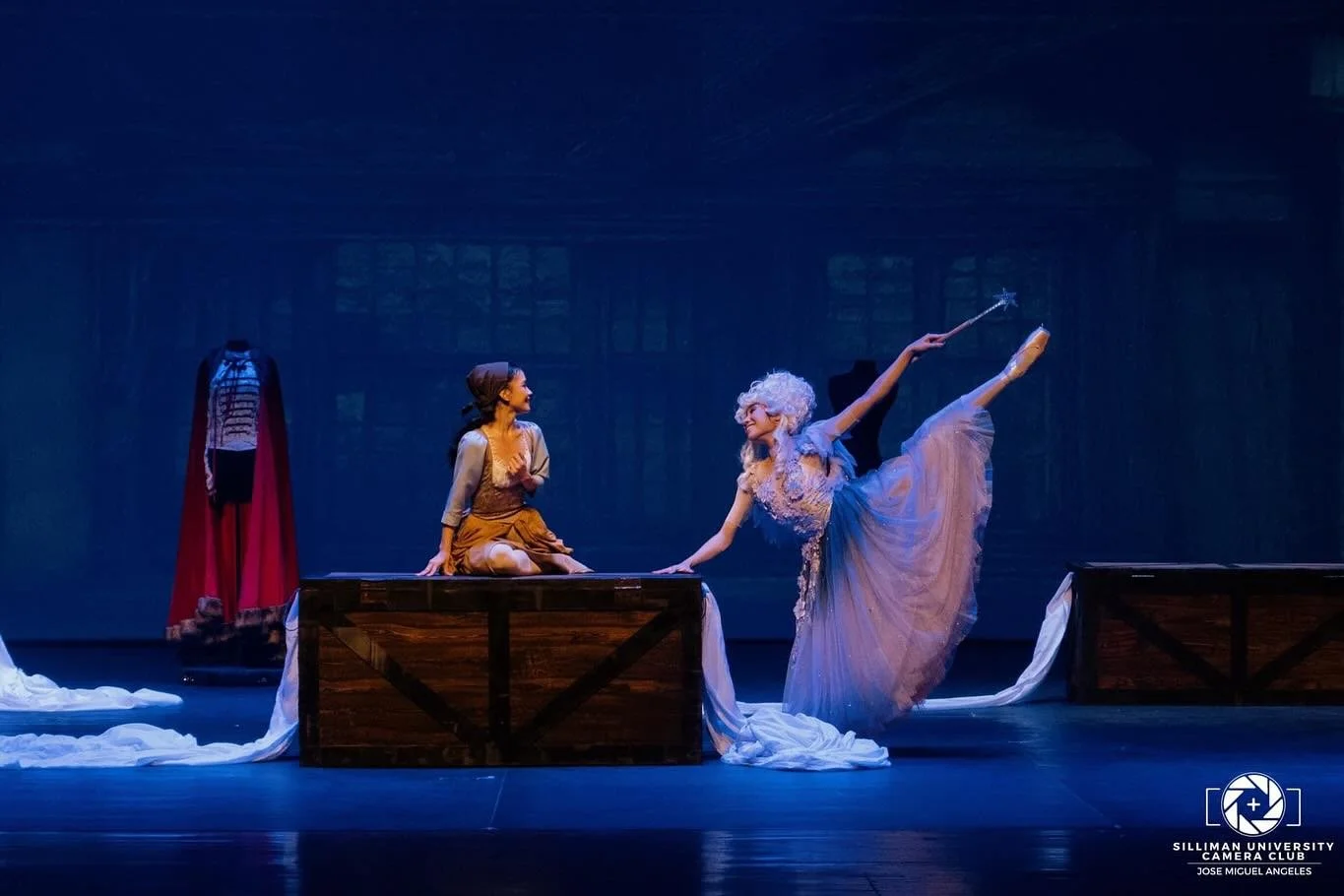    A forlorn Cinderella (Shaira Comeros) cheers up when Fairy Godmother (Stephanie Santiago) appears and helps fulfill her wish to attend the grand ball. With a flick of her magic wand, the fairy makes an elegant gown for the young girl to wear and t