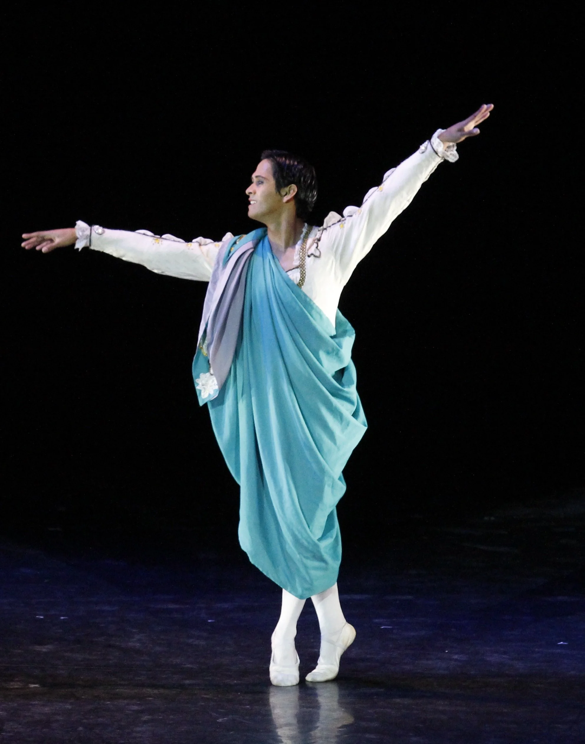    Romeo (Rudy De Dios) is giddy with excitement, having just met Juliet in  Romeo and Juliet . The smitten young man has arranged to see her in secret, with a teal cloak over his white top and tights. Choreographed by Sergey Vikulov, the choreograph