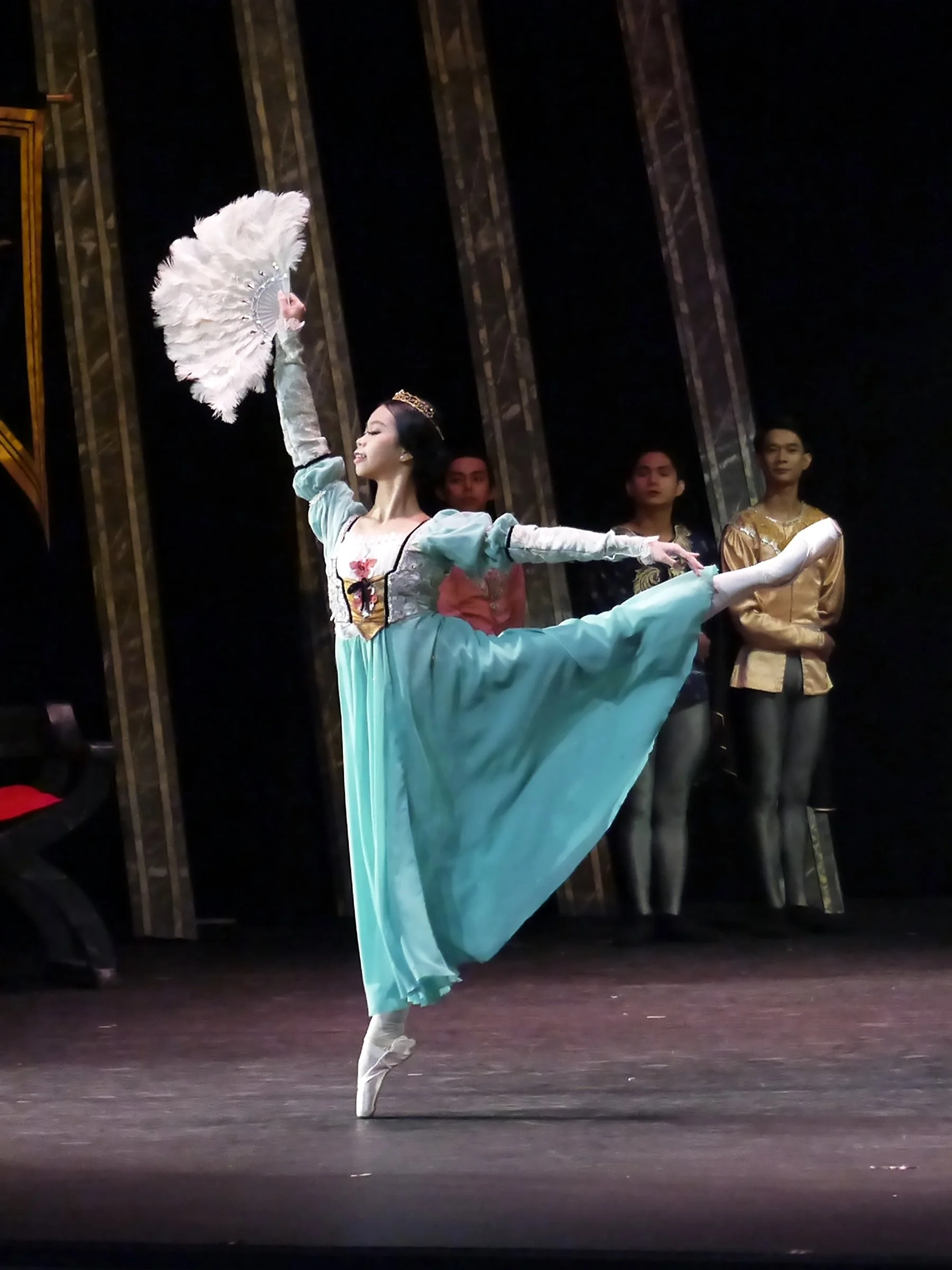    The queen mother in  Swan Lake  (2025) is expecting Prince Siegfried to choose a wife at a ball celebrating his 21st birthday. A bevy of princesses is being introduced to him, including one portrayed by Alene Tan who wears a teal gown and, like th