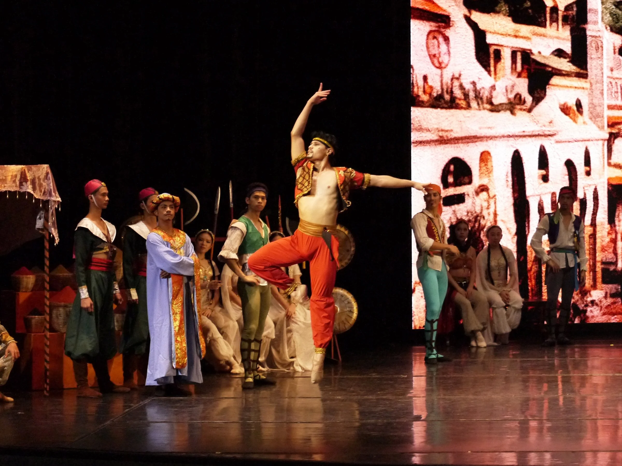    Lankadem (Noah Esplana) makes his presence known in a red ensemble, launching into powerful leaps that reflect his boldness and audacity. He is a feared character in  Le Corsaire  (2024) as he sells off women as slaves to bidders in the pirate adv