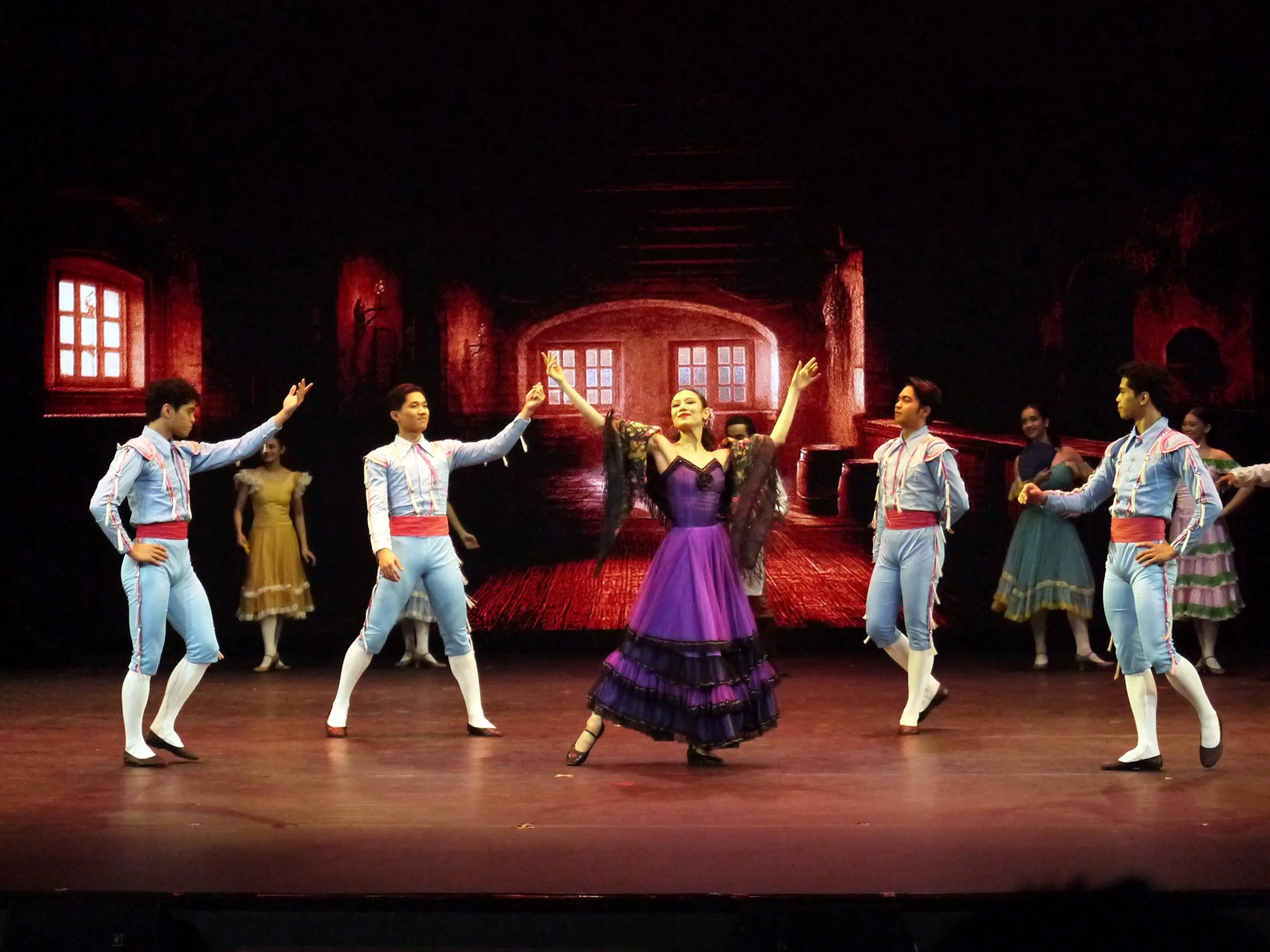    The playful street dancer Mercedes (Abigail Oliveiro) is an instant attention-getter in this scene from  Don Quixote ( 2025) as she is greeted by a group of bullfighters. It’s not just her starkly colored outfit – a violet number with black trimmi
