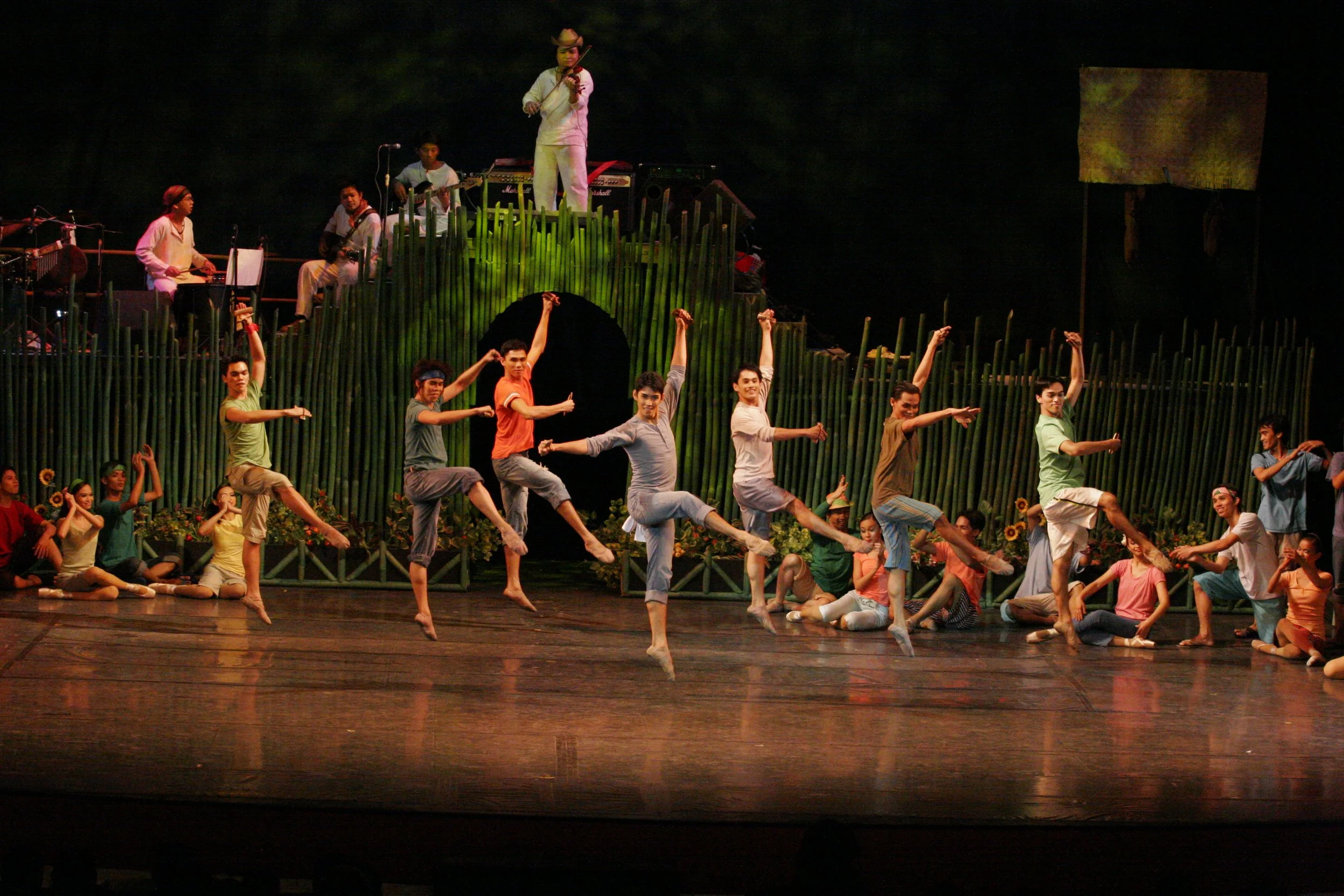    Performing the  subli , men leap, crouch, and strike the ground while using wooden clappers.   