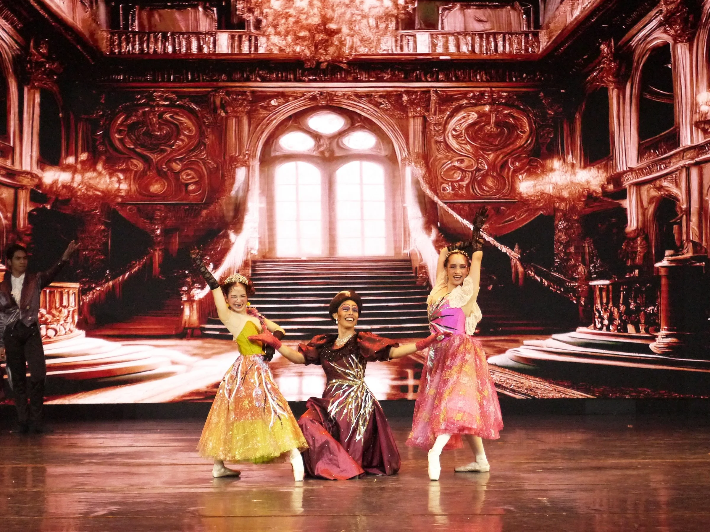    The Stepmother (John Balagot) and her daughters (Jasmine Pia Dames and Judith Po) have tricks up their sleeves to become the center of attention at the ball in Lisa Macuja Elizalde’s  Cinderella  (2023). While the sisters have their own antics, th