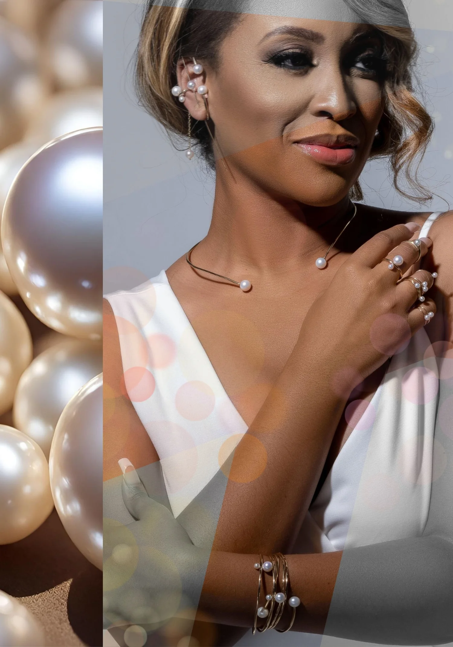 A model wearing a gold ear cuff, an open gold collar necklace, stacked rings and bangles, all set with white pearls