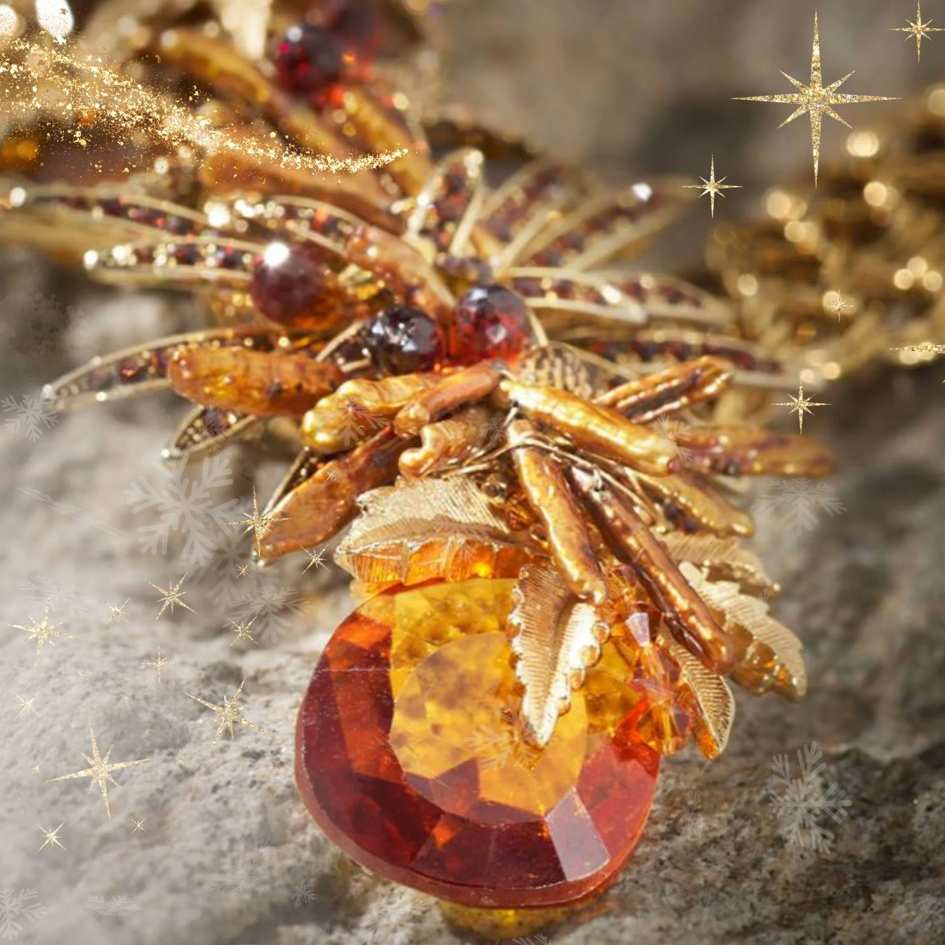 Close-up of an amber and gold statement necklace with warm-toned crystals, holiday sparkle overlays, and a faceted drop pendant.
