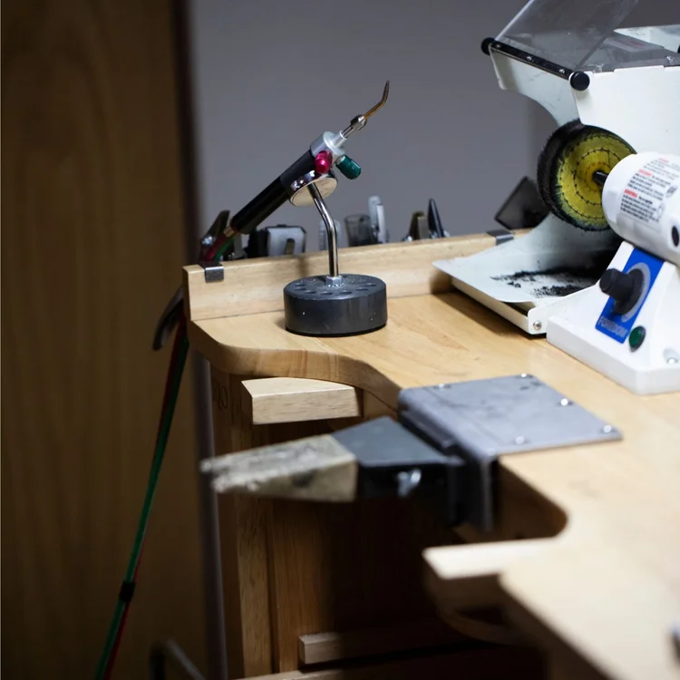 Her empty wooden jeweler's bench with a torch, bench pin and polishing motor