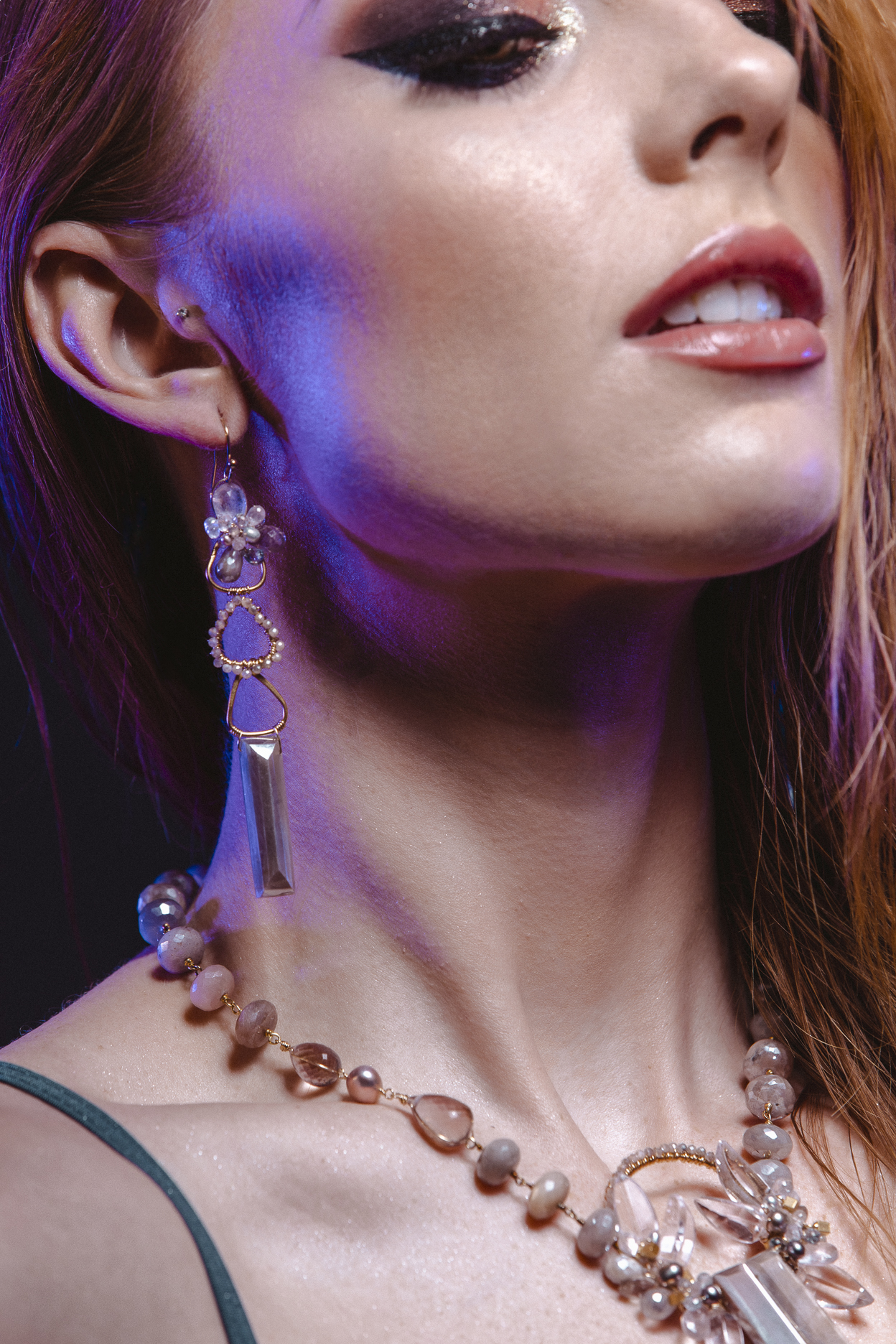 Model wearing long pendant gemstone earrings