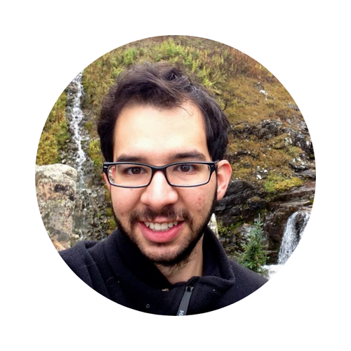 Rodolfo R. in glasses, smiling outdoors beside a waterfall