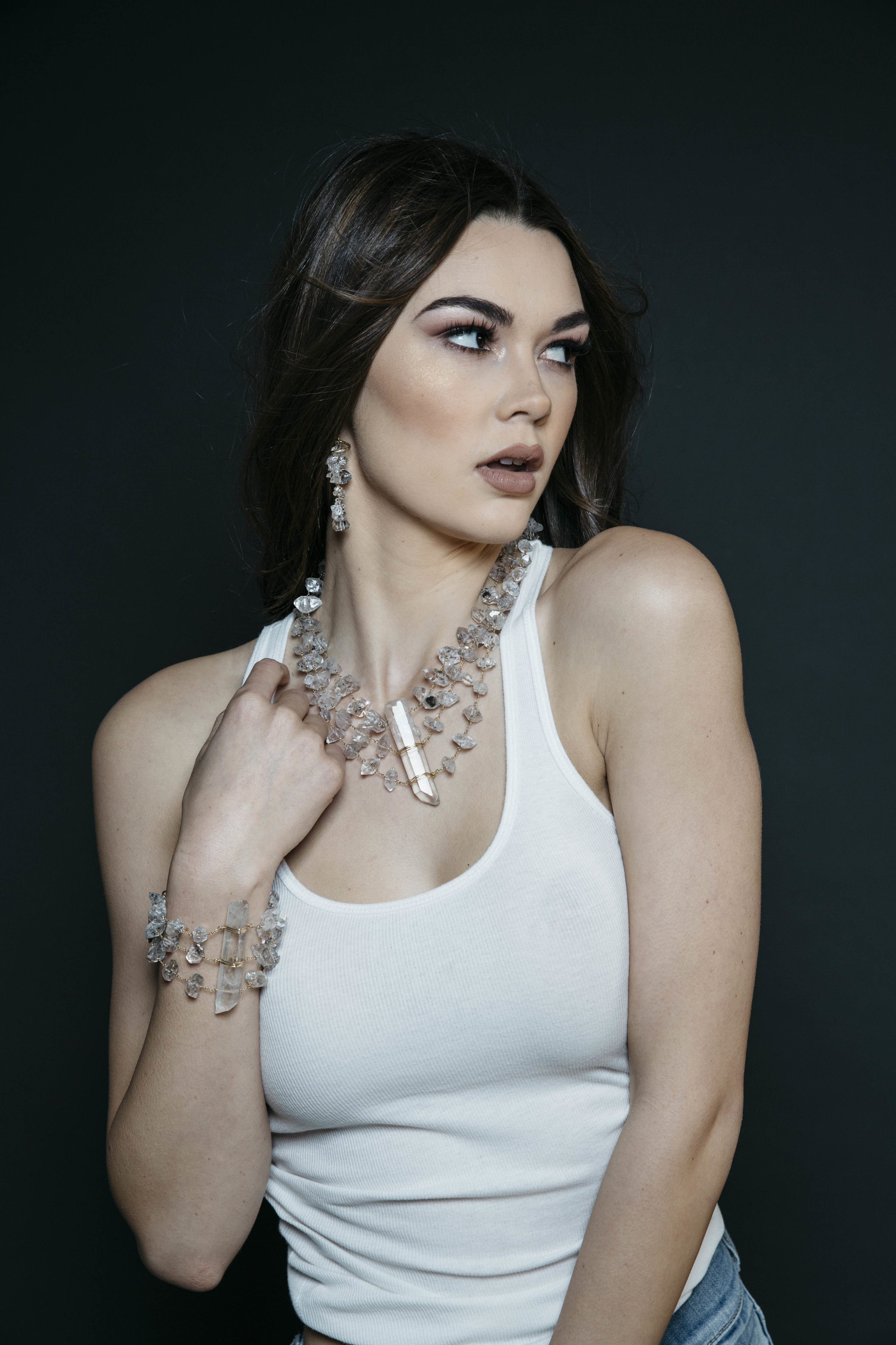 Model wearing a triple strand herkimer diamond statement cuff bracelet with a long crystal point centerpiece