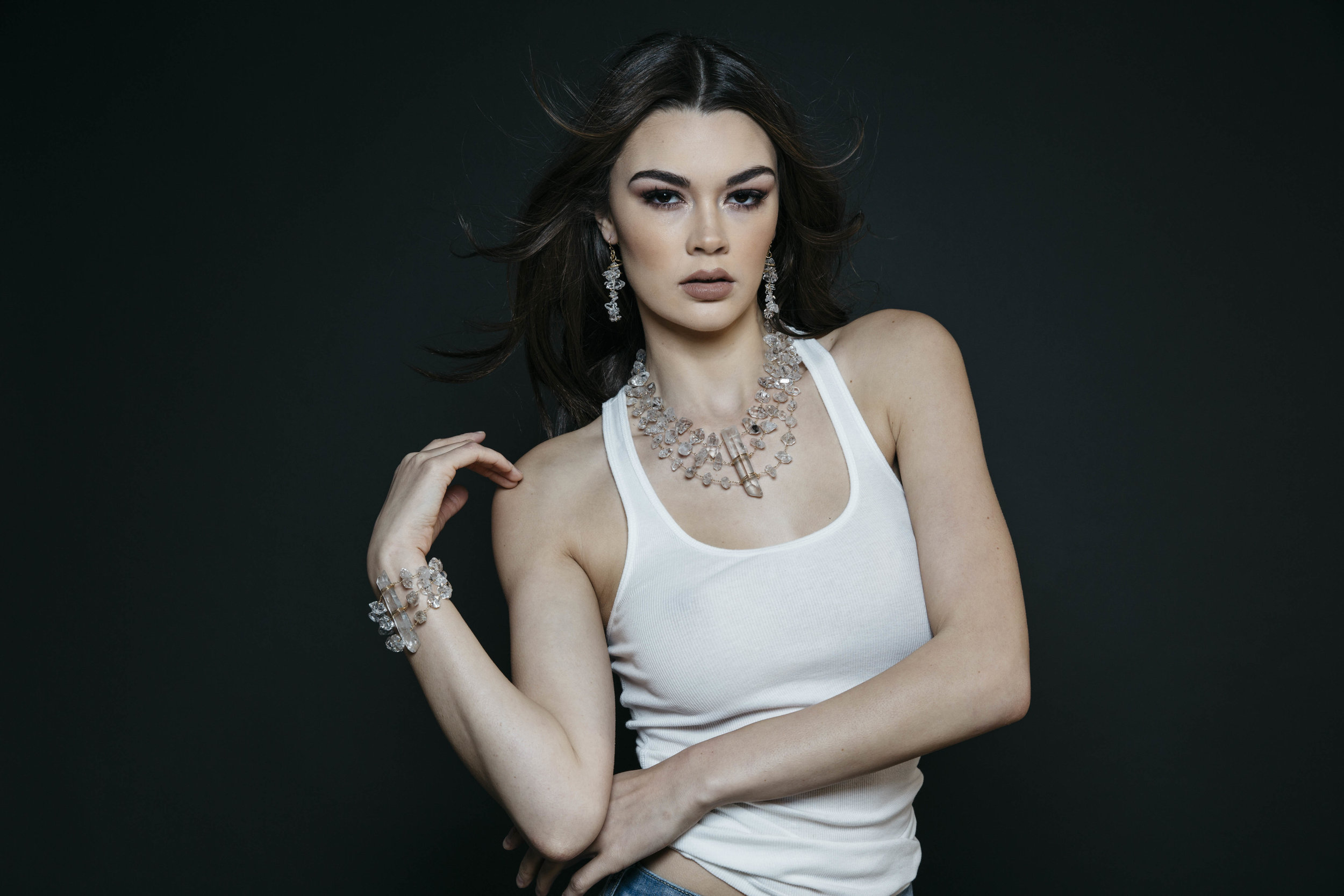 Model wearing a triple strand herkimer diamond statement cuff bracelet with a long crystal point centerpiece