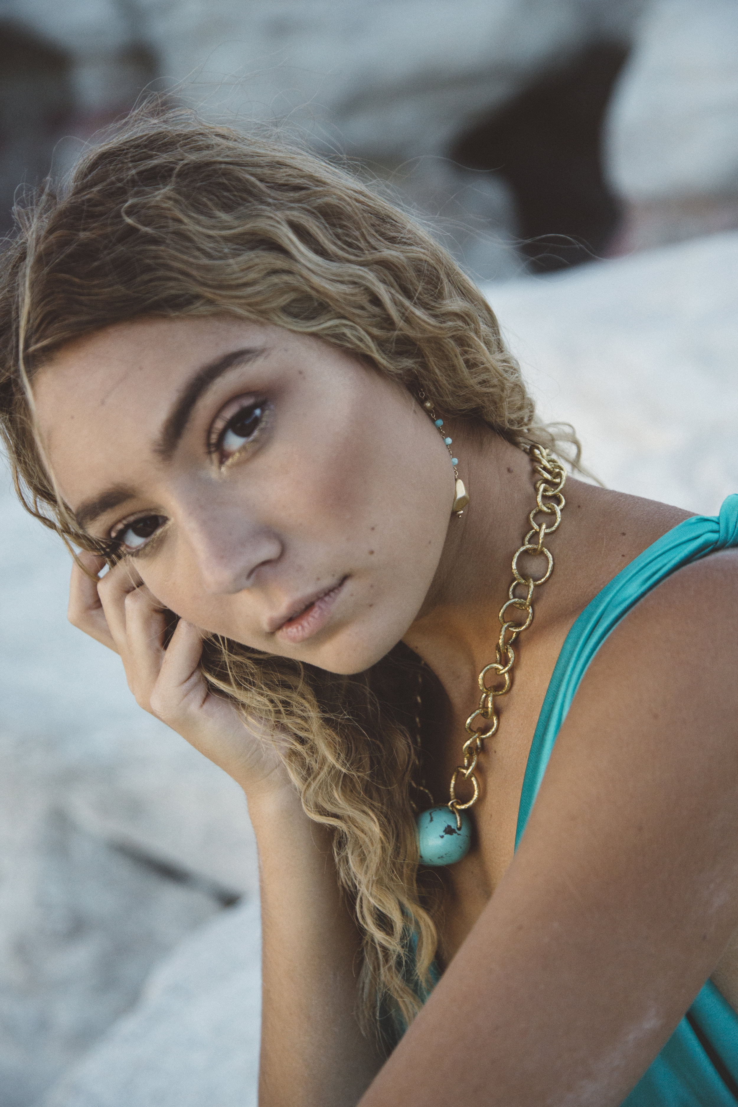 Model wearing a chunky gold chain collar necklace with a turquoise nugget