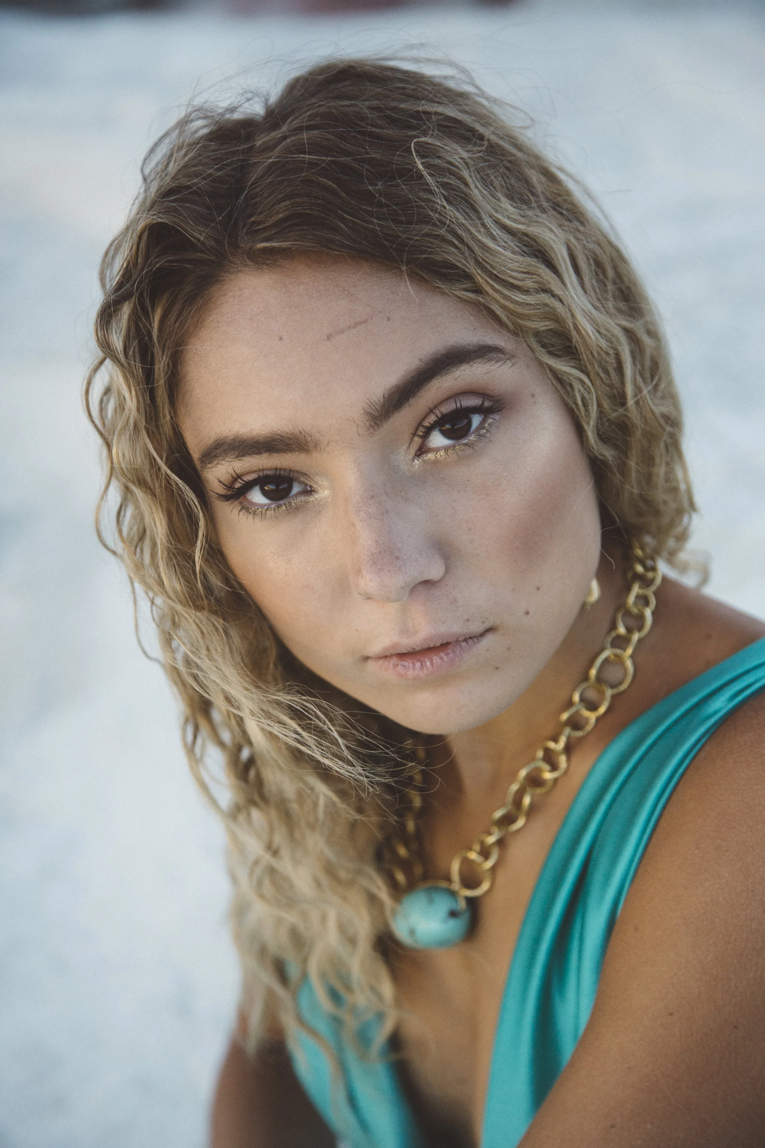 Model wearing a chunky gold chain collar necklace with a turquoise nugget