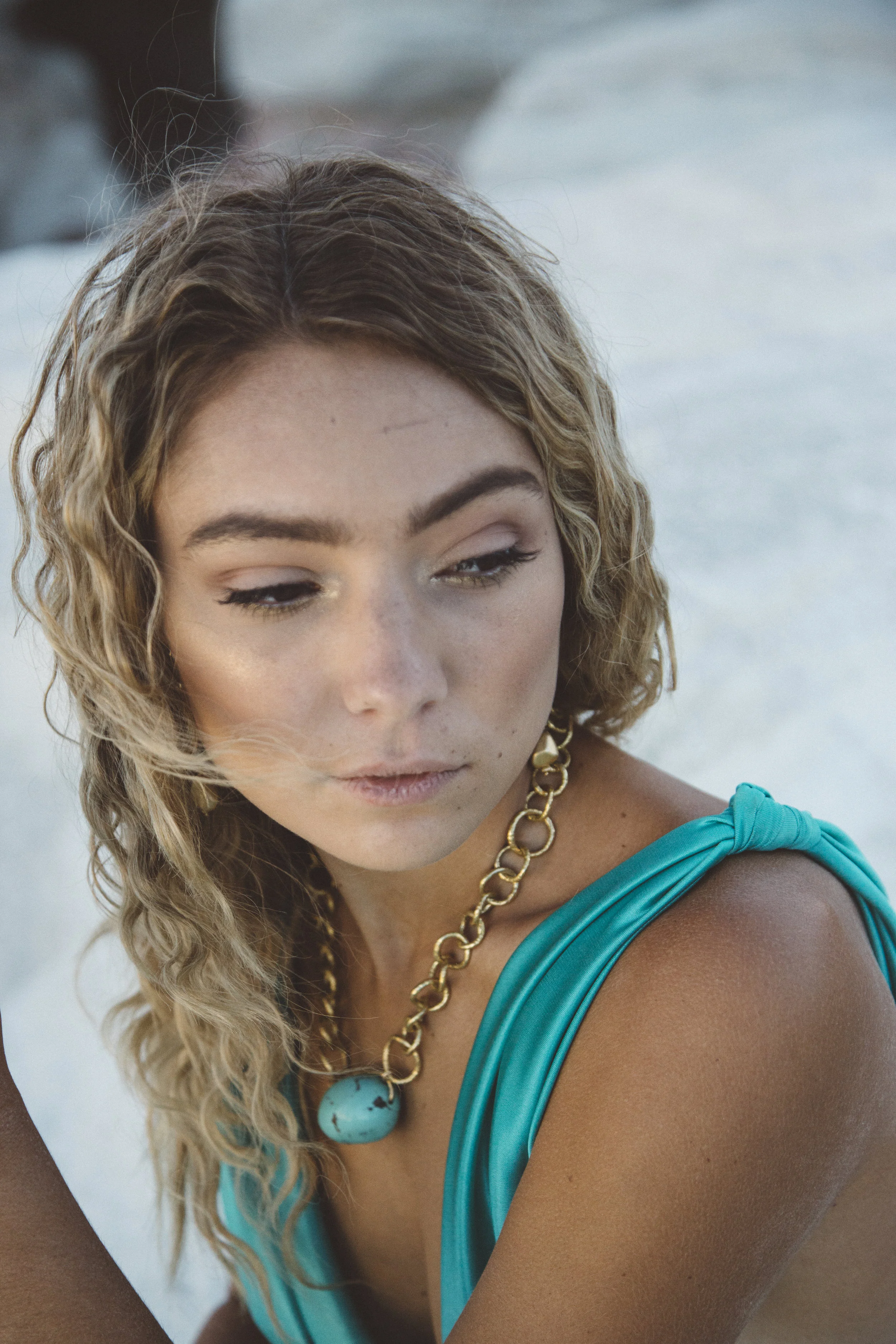 Model wearing a chunky gold chain collar necklace with a turquoise nugget