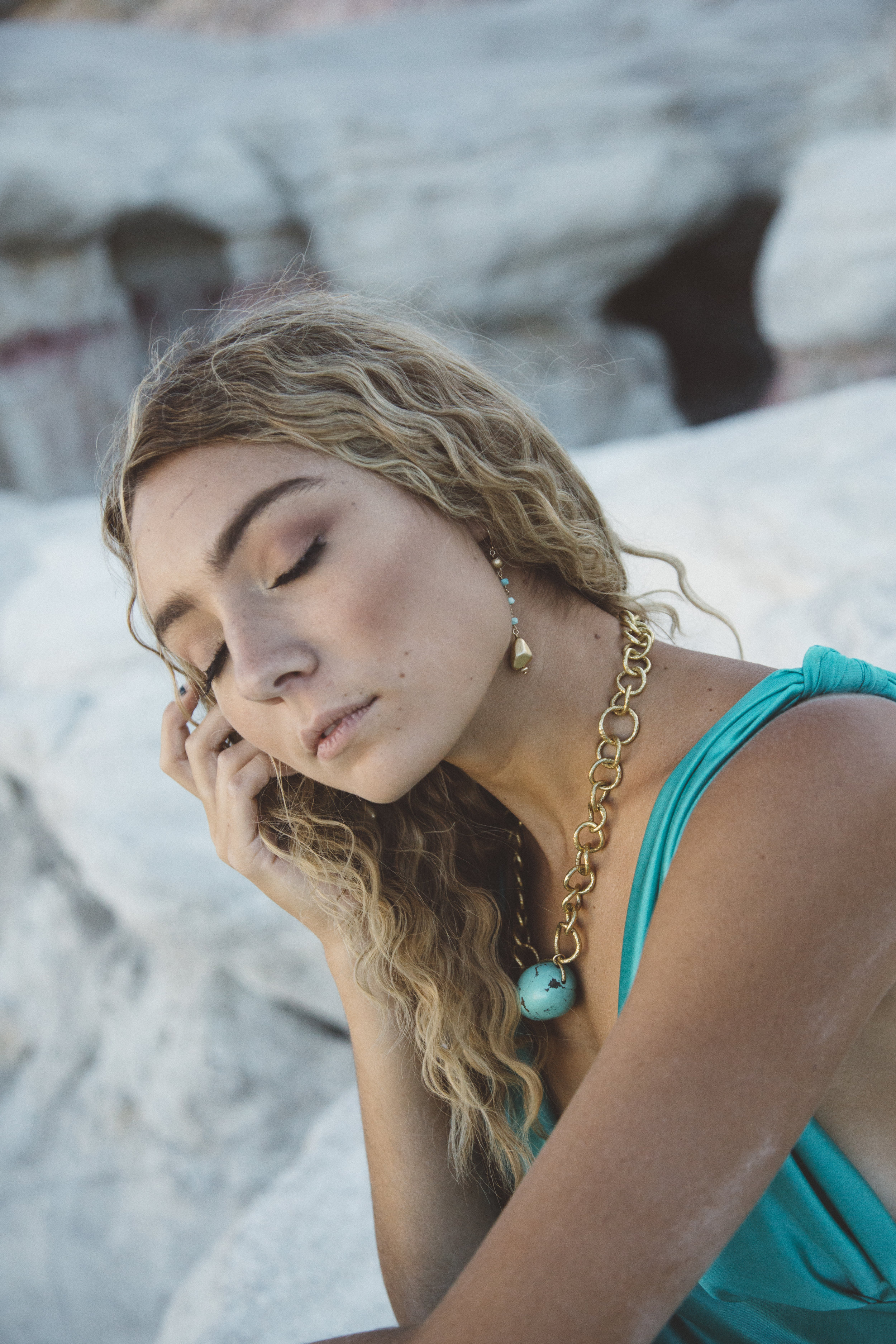 Model wearing a chunky gold chain collar necklace with a turquoise nugget