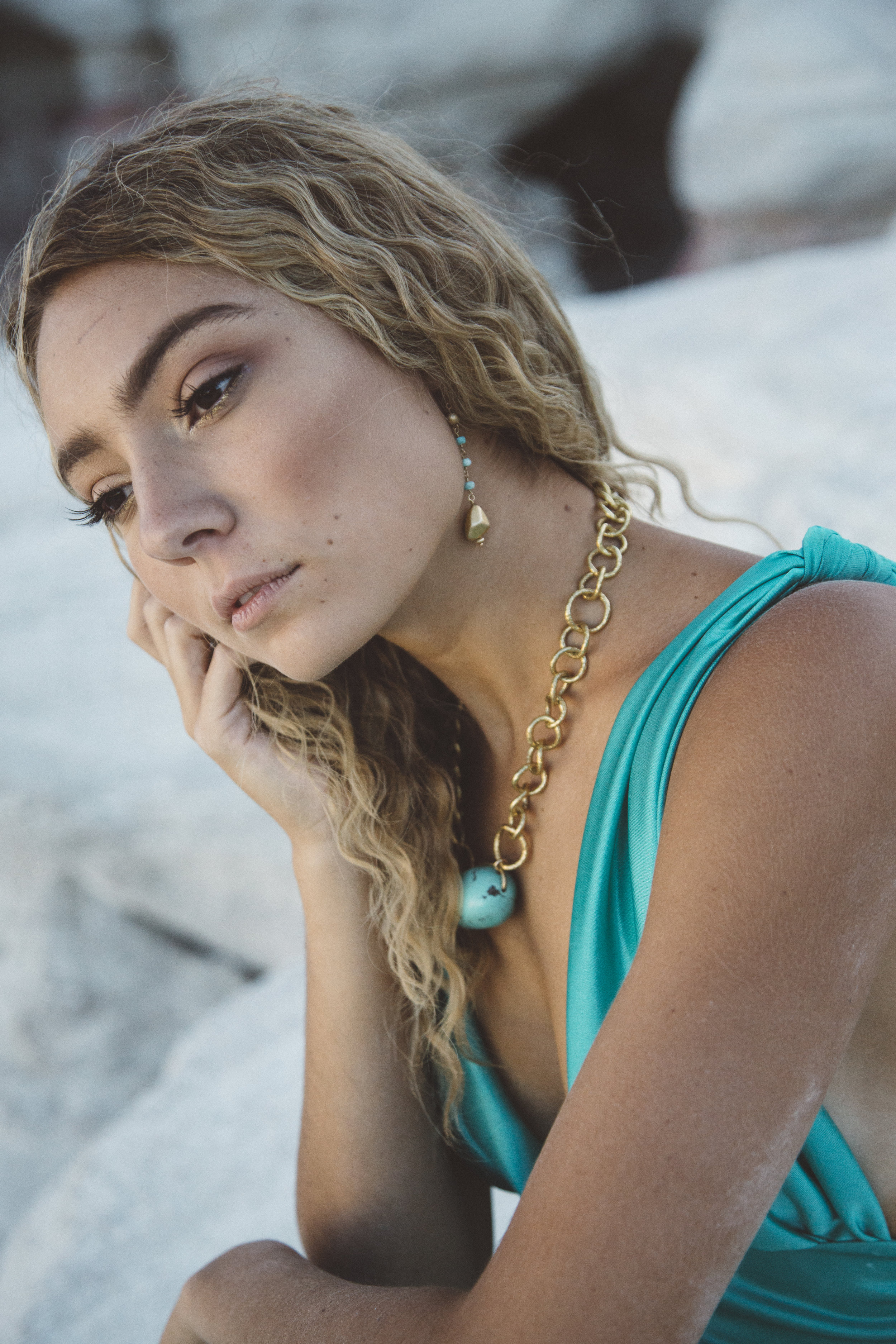 model wearing turquoise with a gold drop pendant earrings