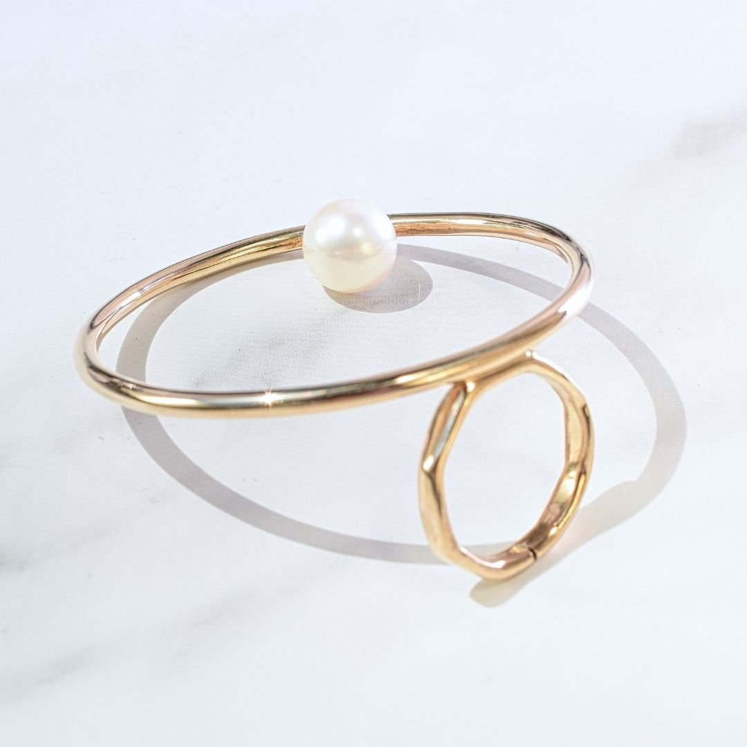 Side angle view of the large open circle gold ring with pearl, emphasizing its modern and sleek design