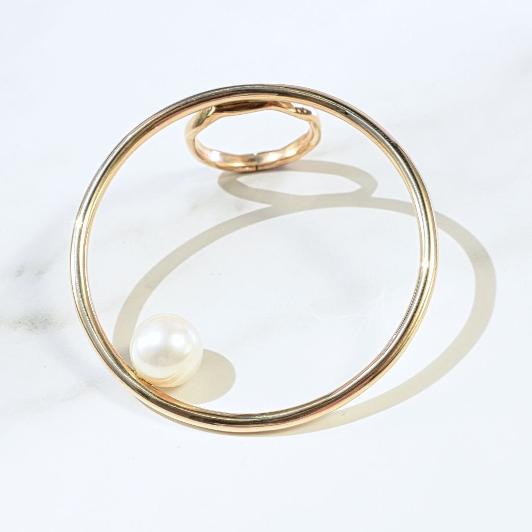 Side angle view of the large open circle gold ring with pearl, emphasizing its modern and sleek design