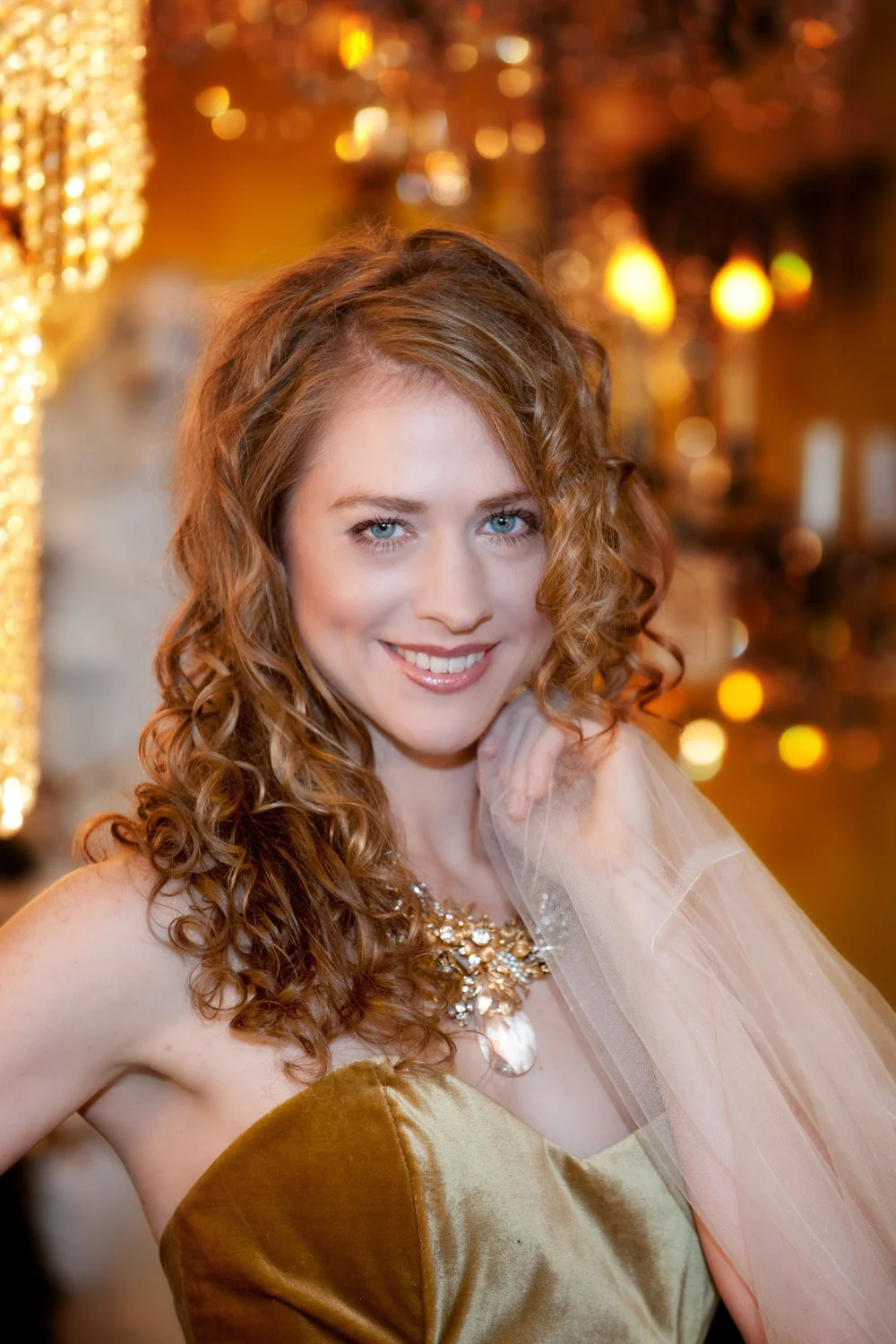 Curly haired woman in brown dress with gold necklace
