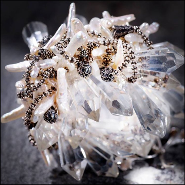 A cluster of clear crystal points and white stick pearls with dark wire-wrapped accents
