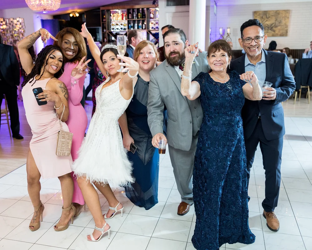 Wedding guests dancing at the reception, a woman in a navy lace gown at the center