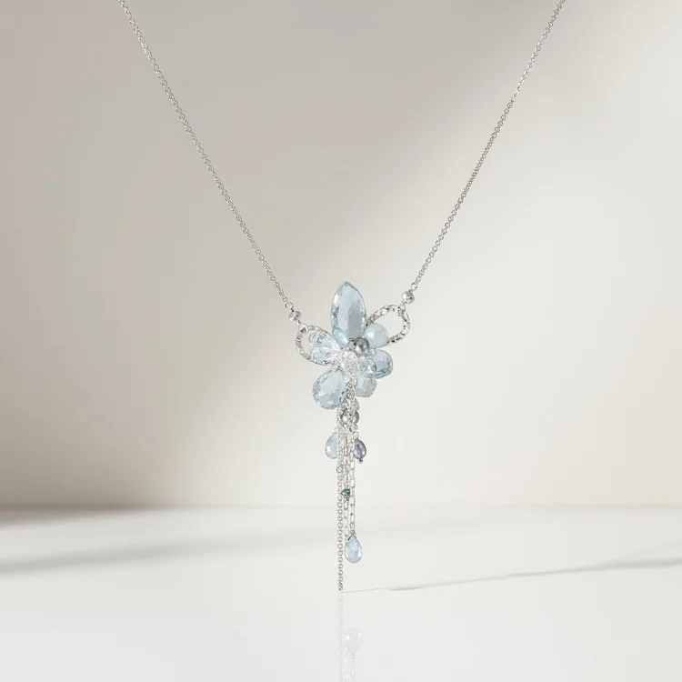 A delicate silver pendant necklace with a cluster of pale aqua stones and a fine drop