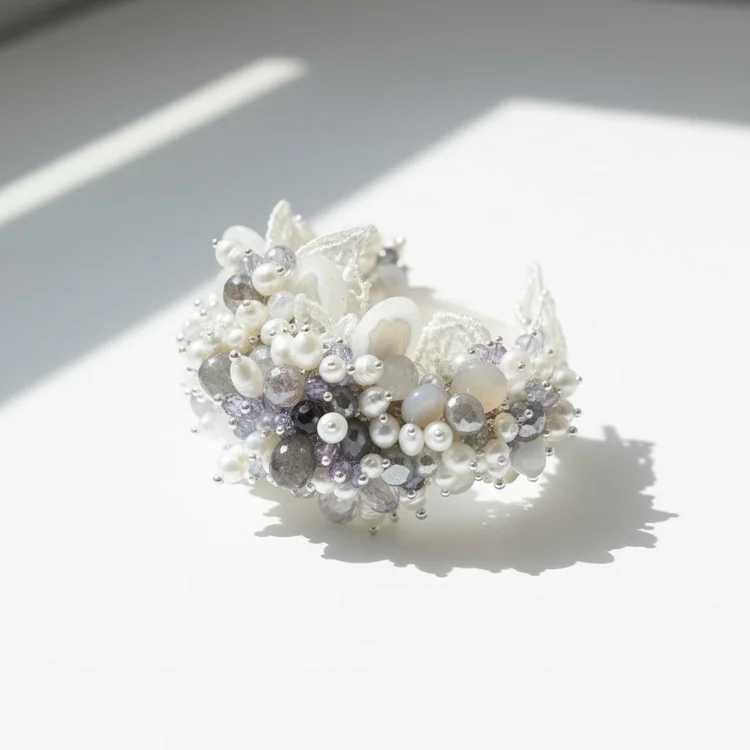 A cuff clustered with white pearls, crystals and gray stones