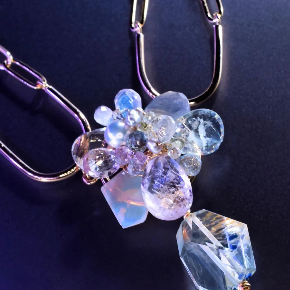 A pastel gemstone drop pendant necklace from the Tamar collection by Andrea Li, on purple