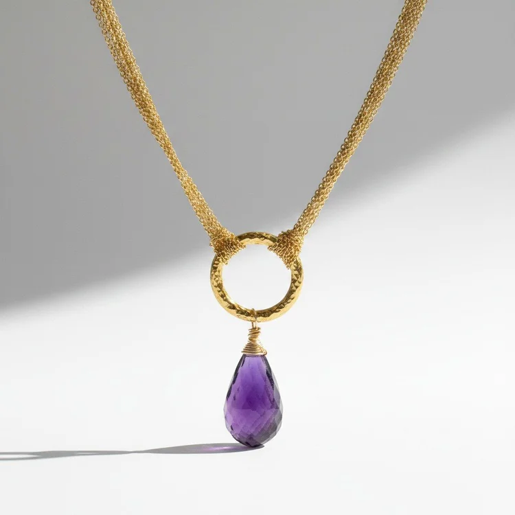 Gold mesh necklace with a hammered gold ring and a faceted violet teardrop