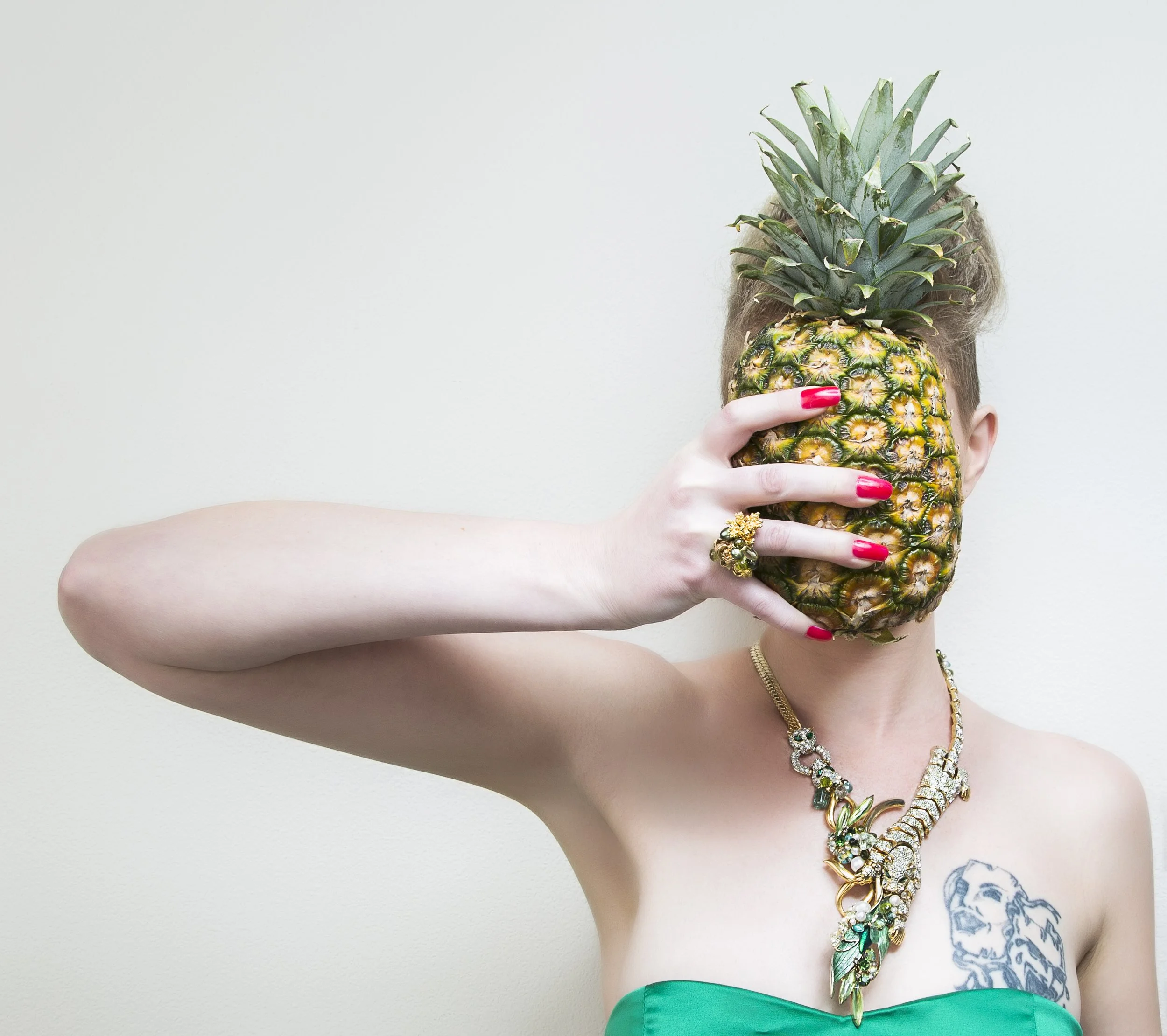 model holding a pineaplly in front of her face wearing a statement necklace