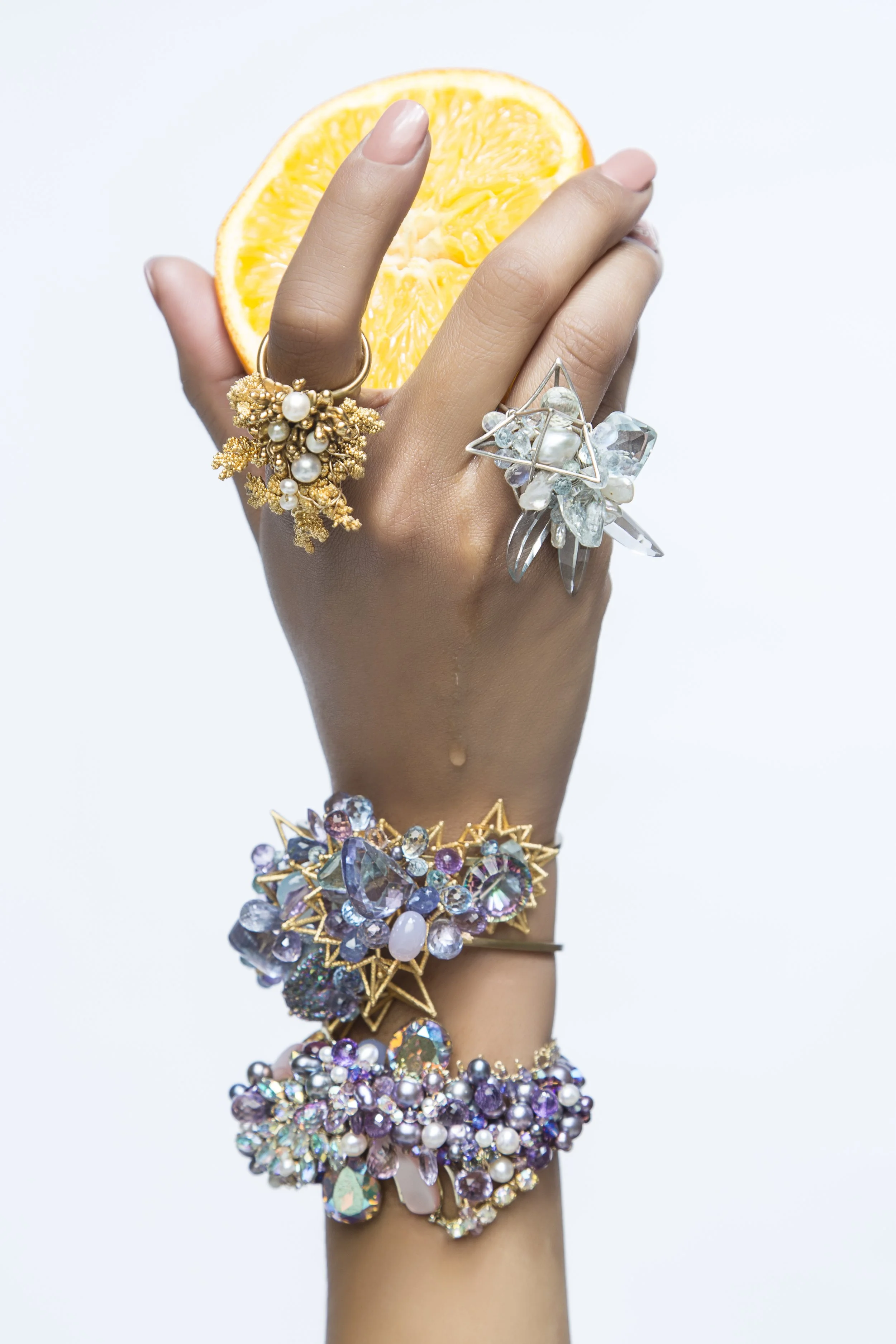 model hand holding a lemon wearing multiple statement bracelets and rings