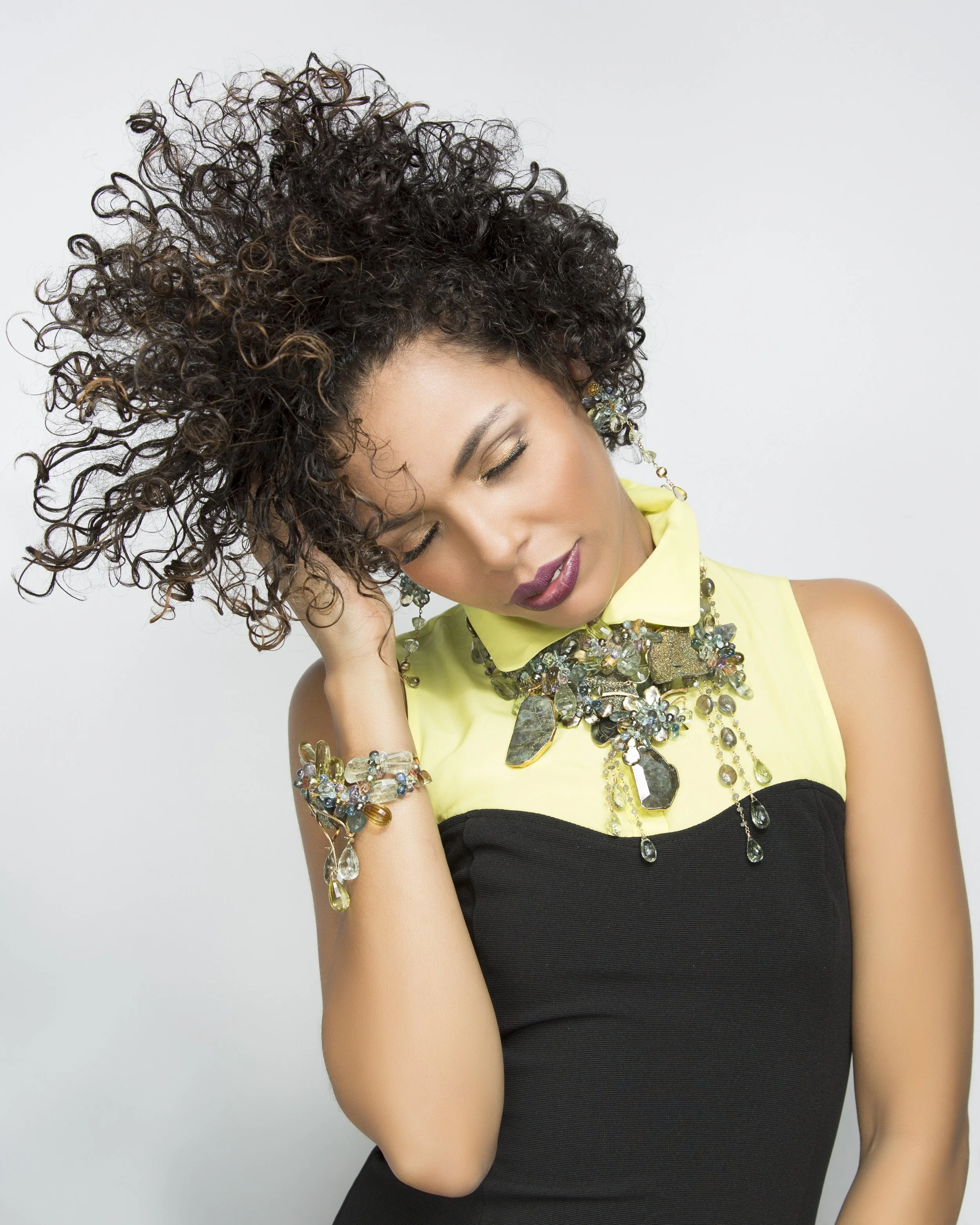 model with wild hair flowing wearing multiple statement necklaces