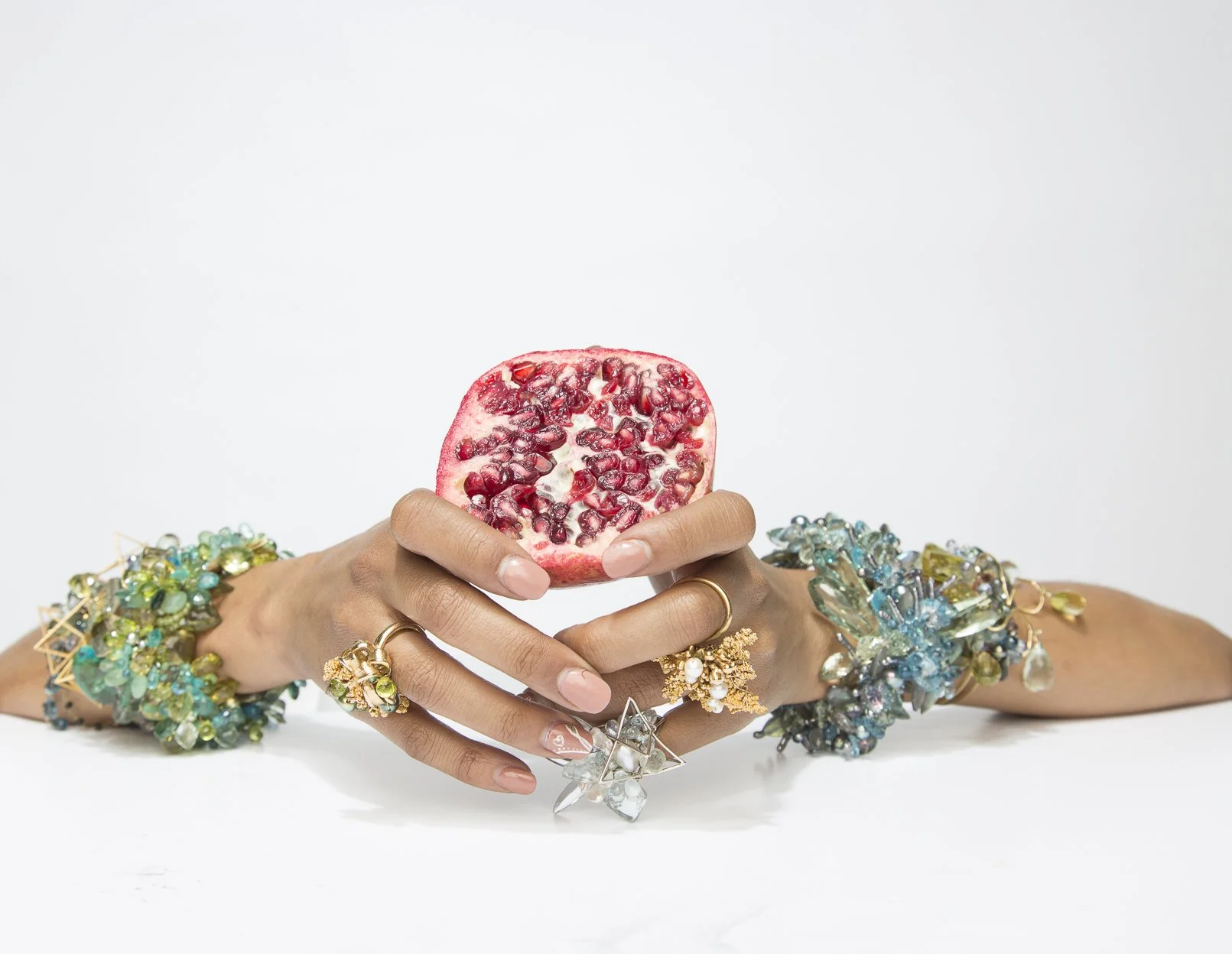 model holding a pomegranate wearing statement gemstone bracelets 