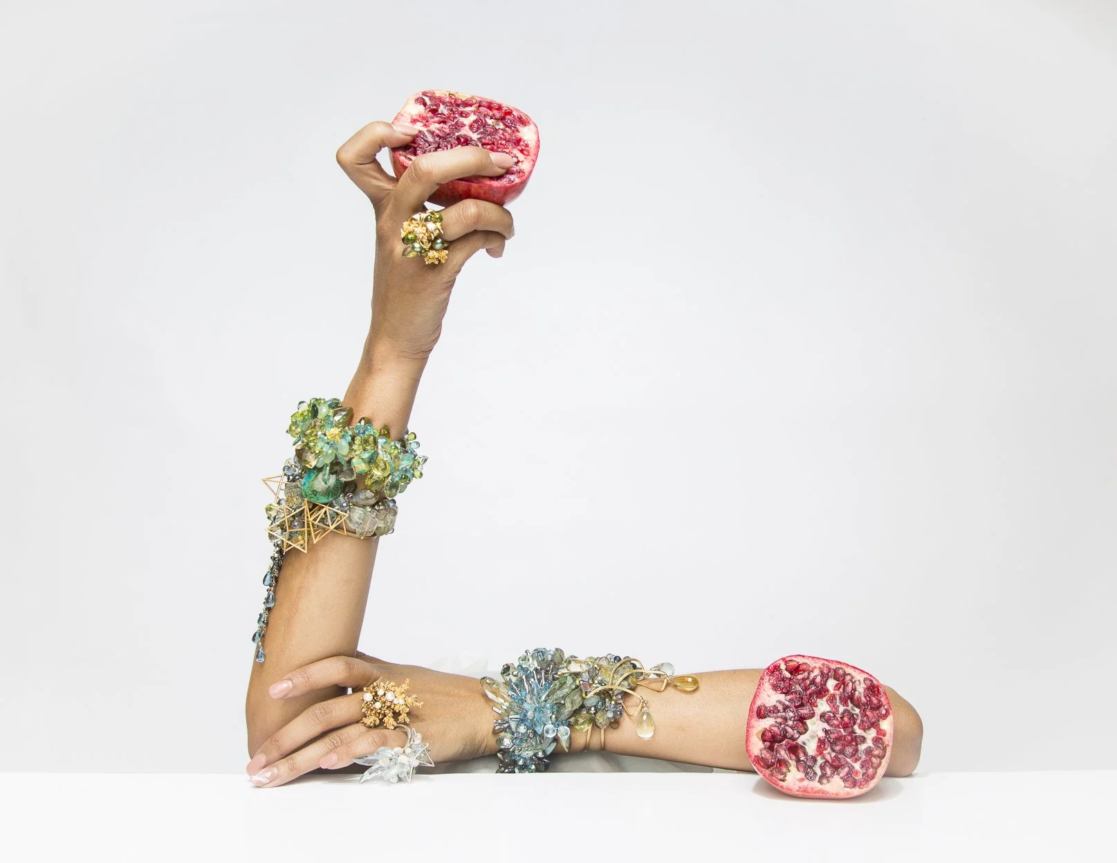 model holding a pomegranate wearing statement gemstone bracelets 