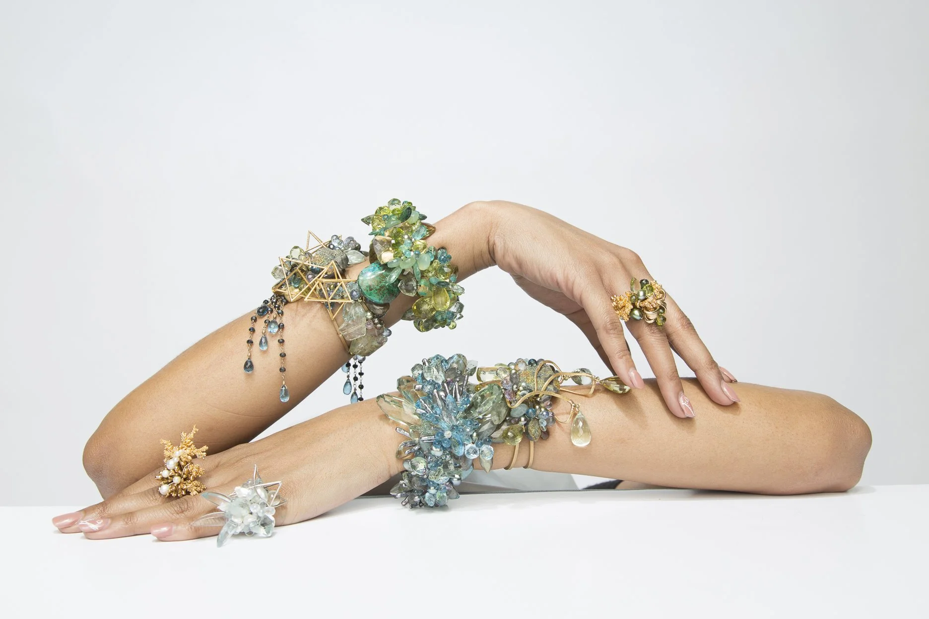 model arms on a table wearing multiple statement gemstone bracelets
