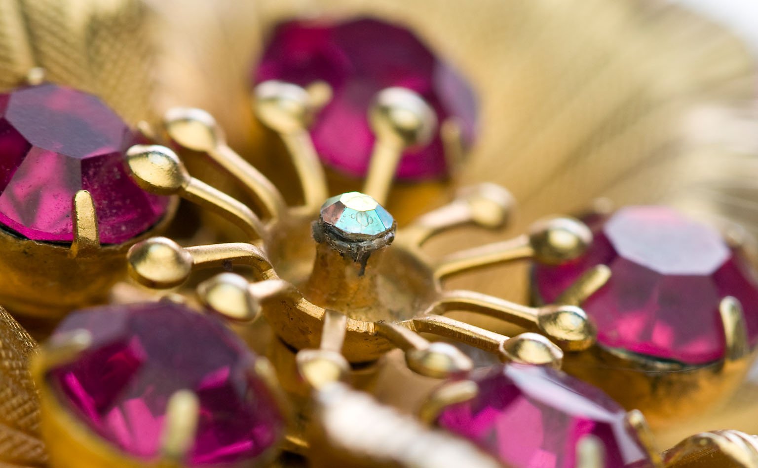 Detail of prong-set fuchsia rhinestones and gold petal work
