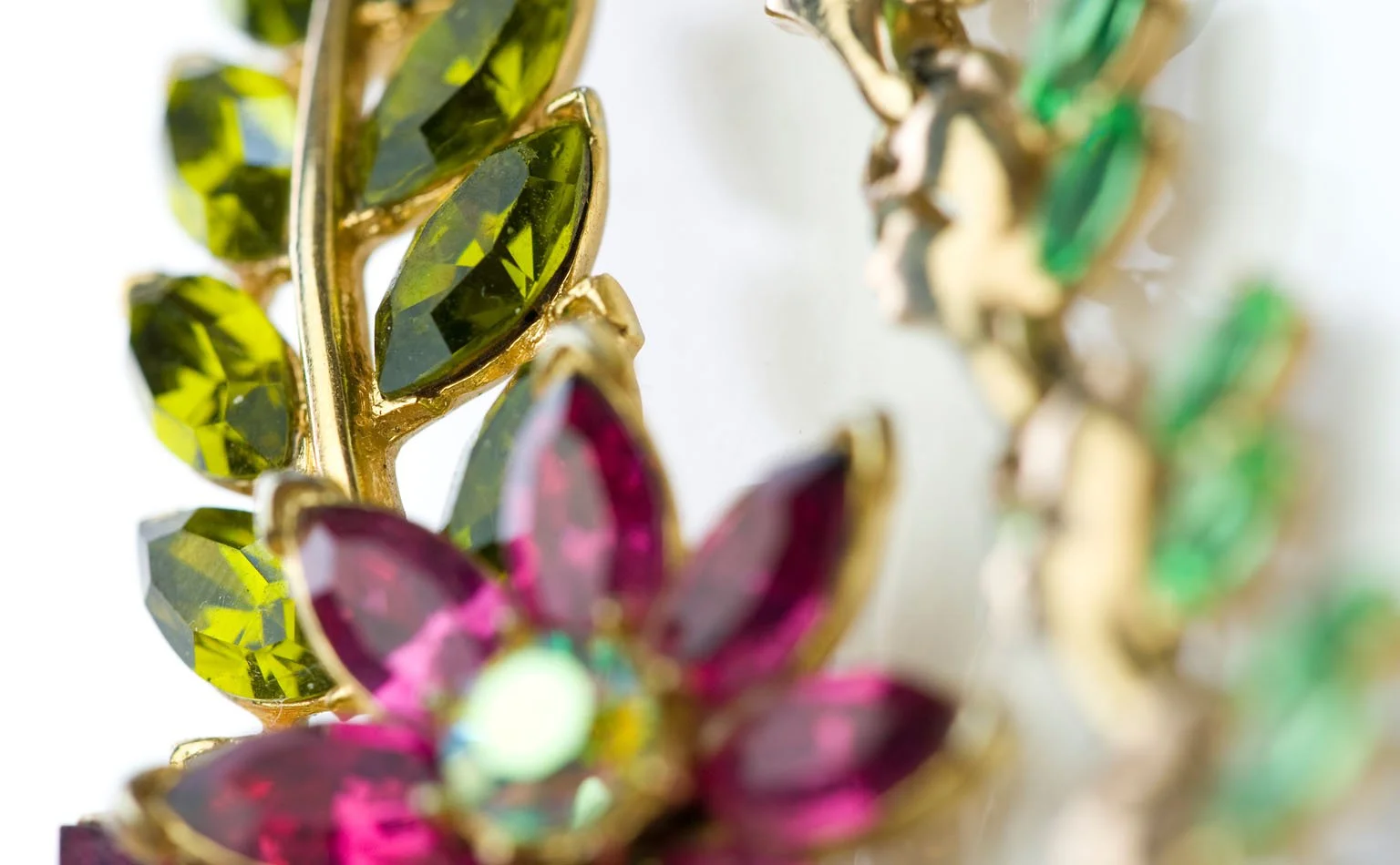 Detail of green navette leaves framing a fuchsia rhinestone flower