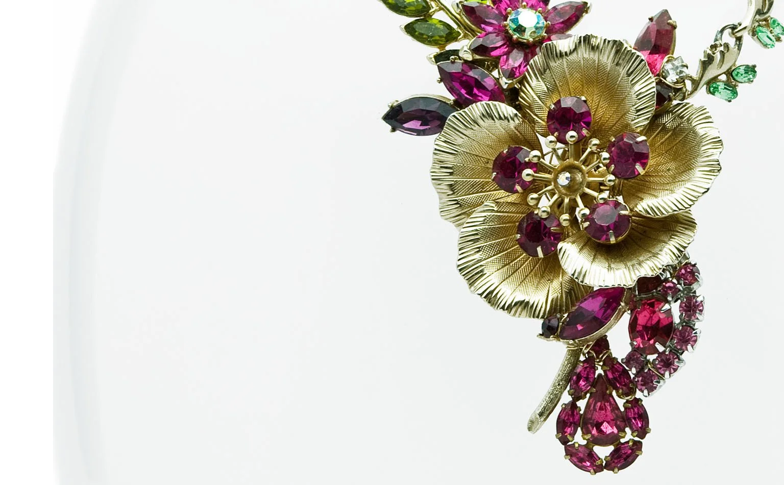 Gold-tone flower centering a fuchsia and green rhinestone cluster