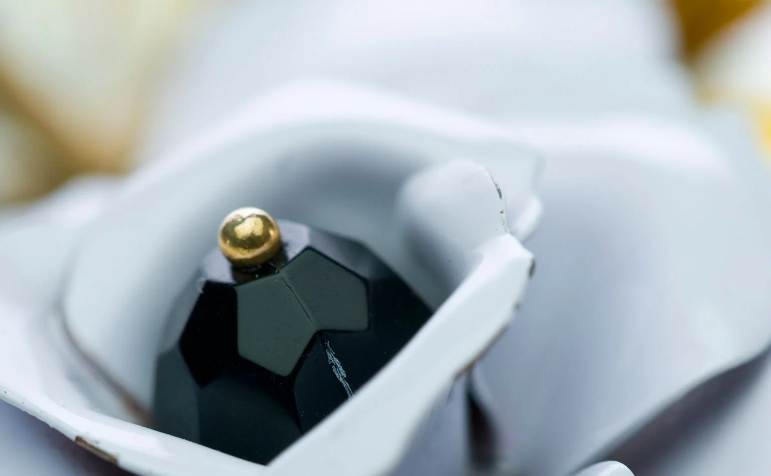 Detail of a black faceted crystal set inside a white enamel flower