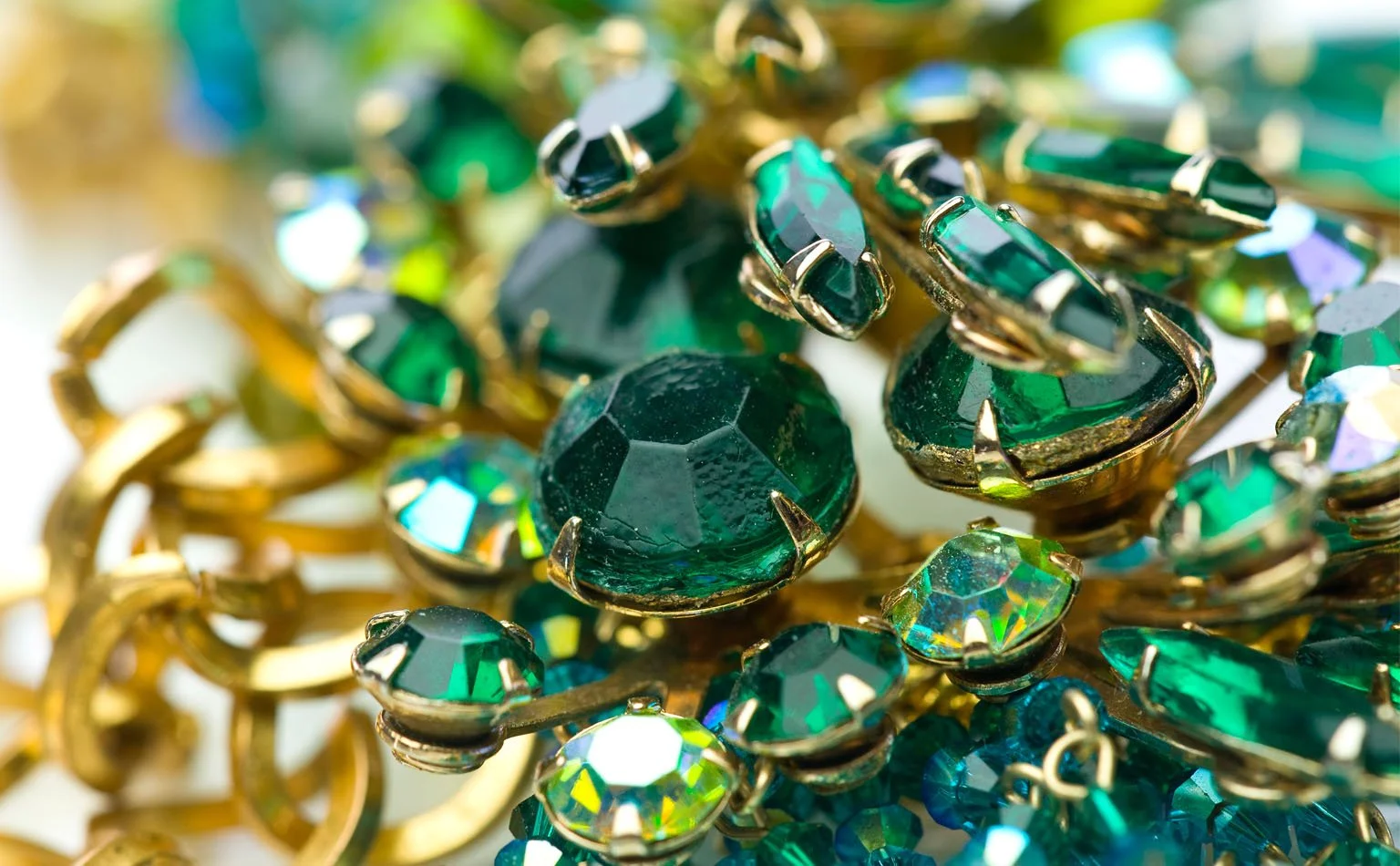 Detail of emerald rhinestones threaded through heavy gold chain