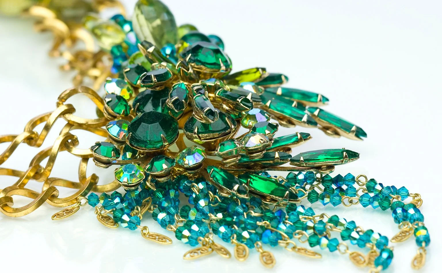 Detail of emerald rhinestones threaded through heavy gold chain 