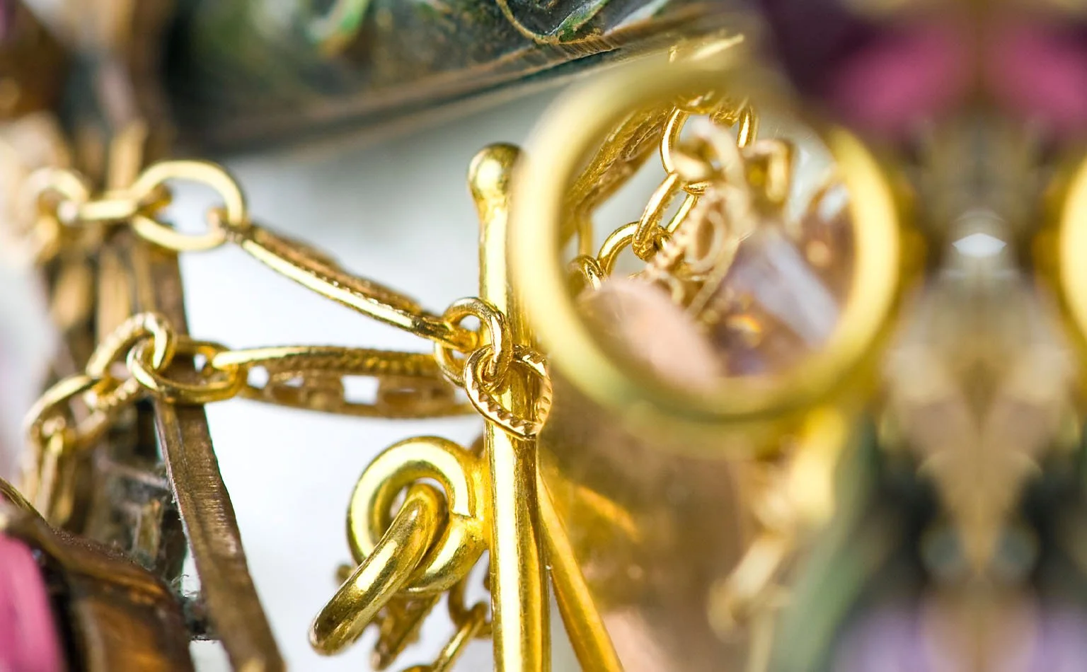 Detail of gold-tone links beside amethyst and pink crystal