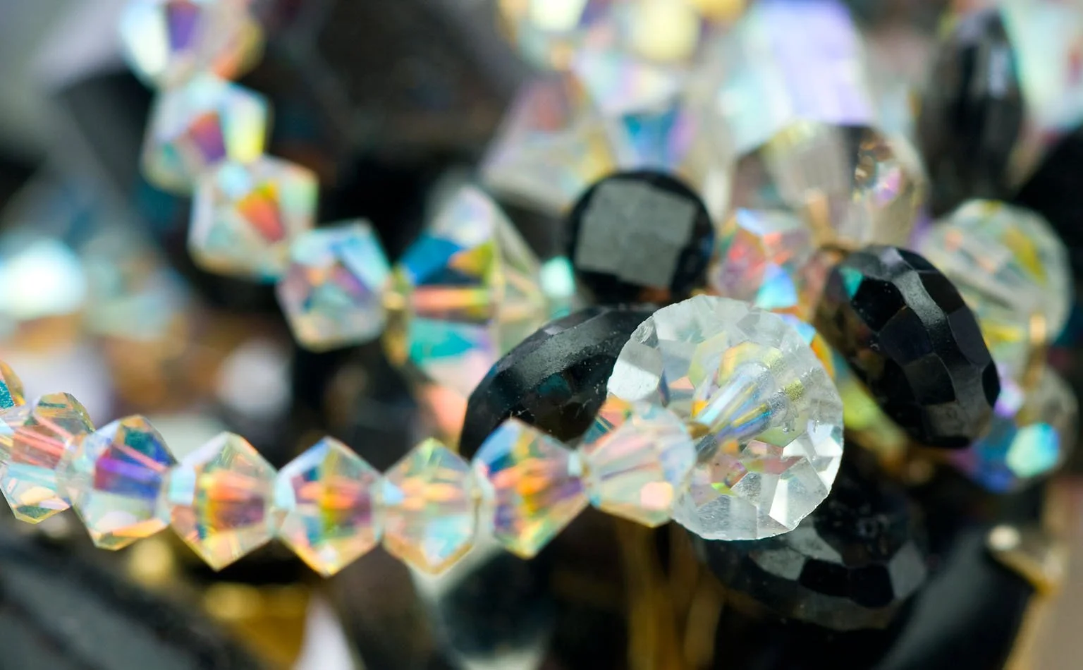 Detail of aurora borealis crystal beading against black faceted stones