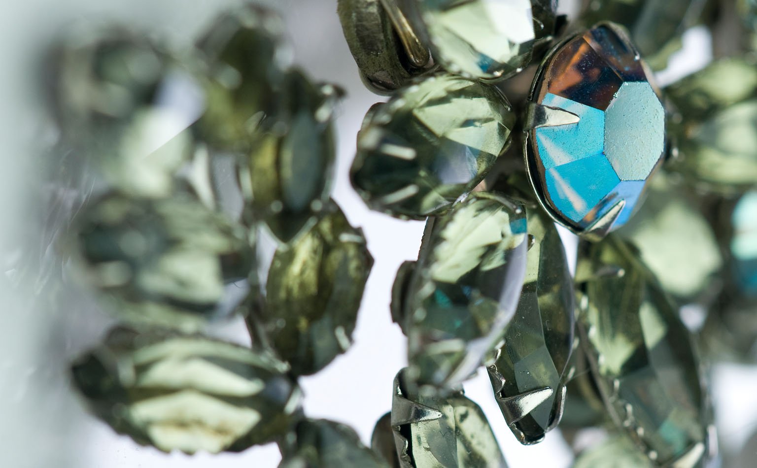 Detail of smoky grey navette crystal around a blue-green center stone