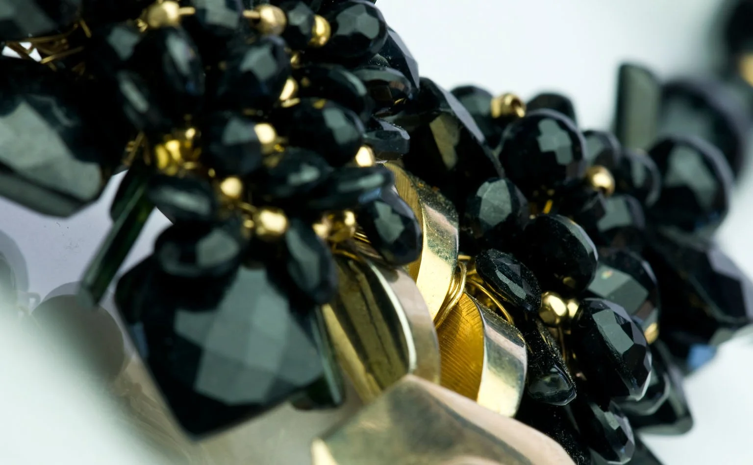 Detail of faceted black crystal beading against polished gold 