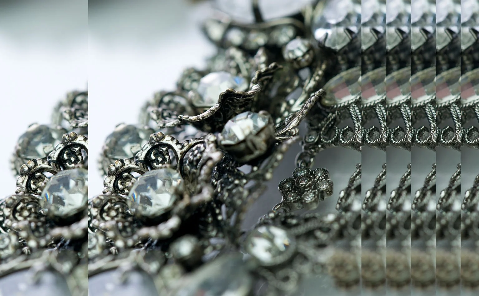 Detail of a rhinestone and pearl panel beside a snake-chain band 