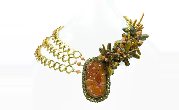 Gold chain necklace centered on a carved carnelian pendant